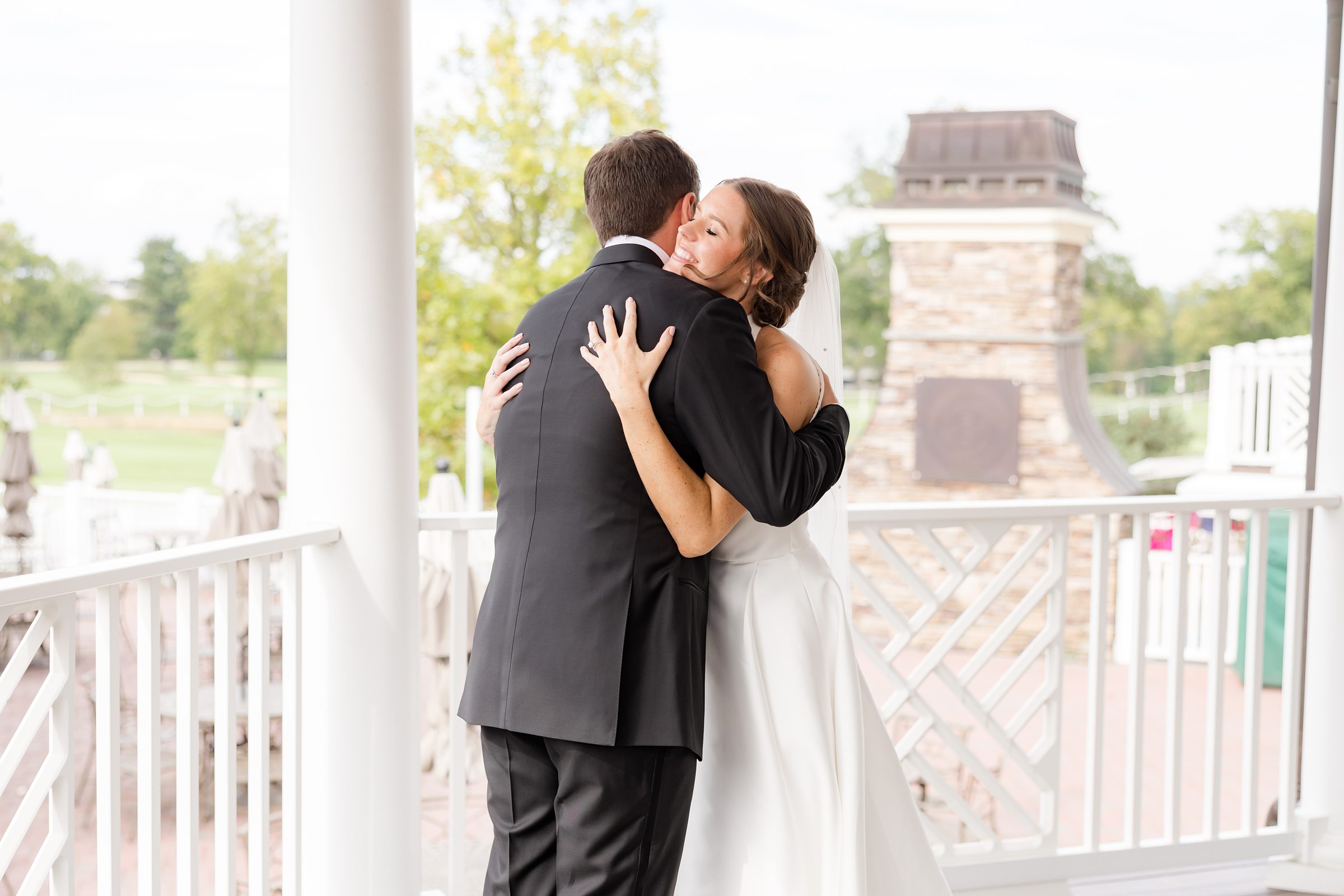 Bride smiles with eyes closed as she hugs her groom, savoring the warmth of their first moments together.