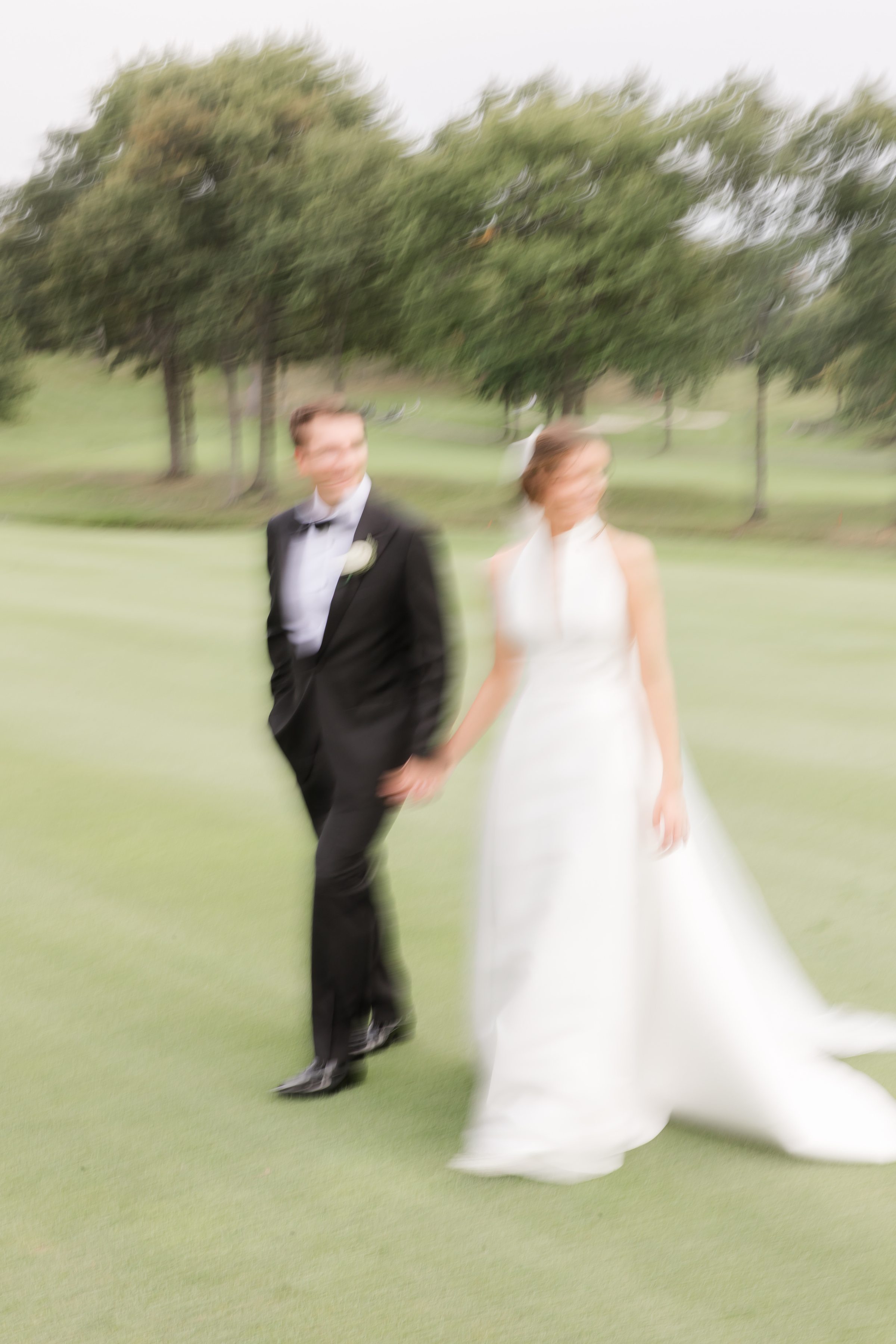 Bride and groom glide across the landscape in a painterly blur, their connection the only thing in focus in a fleeting, romantic scene.