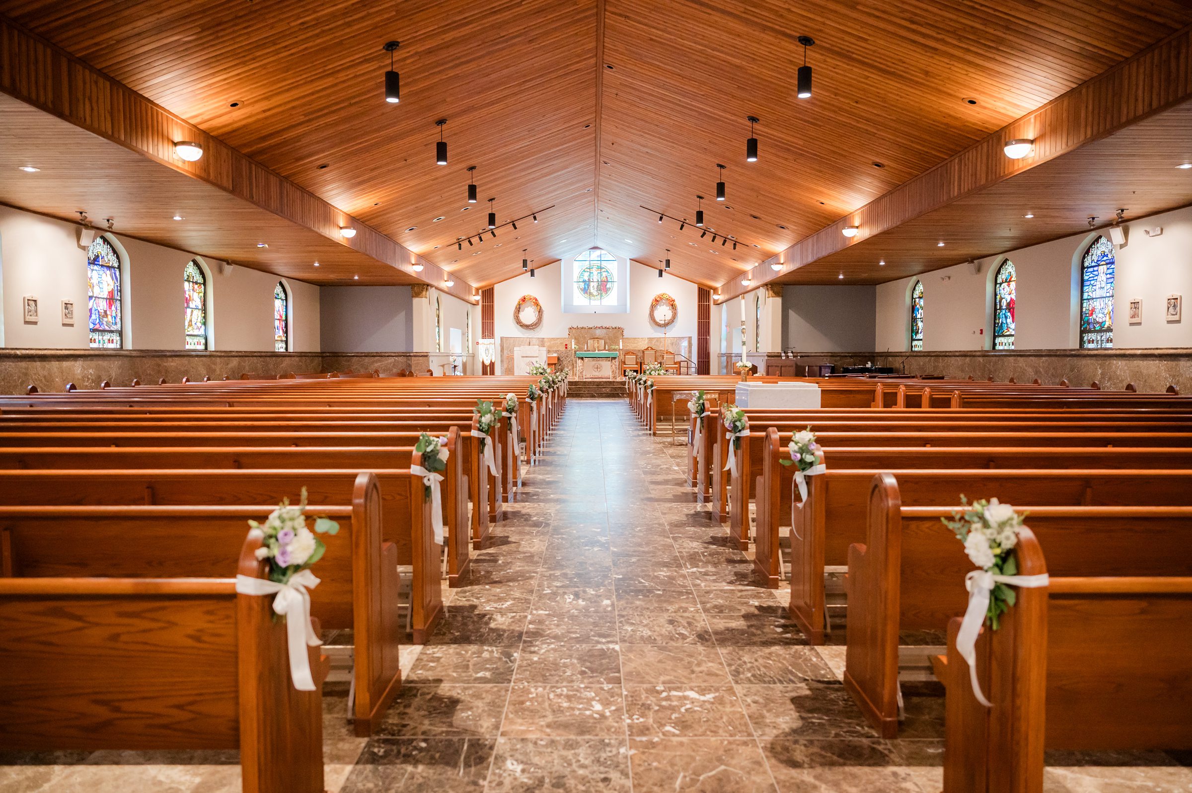 Sunlight fills a quiet church, rows of pews adorned with delicate flowers awaiting the moment two lives will unite.
