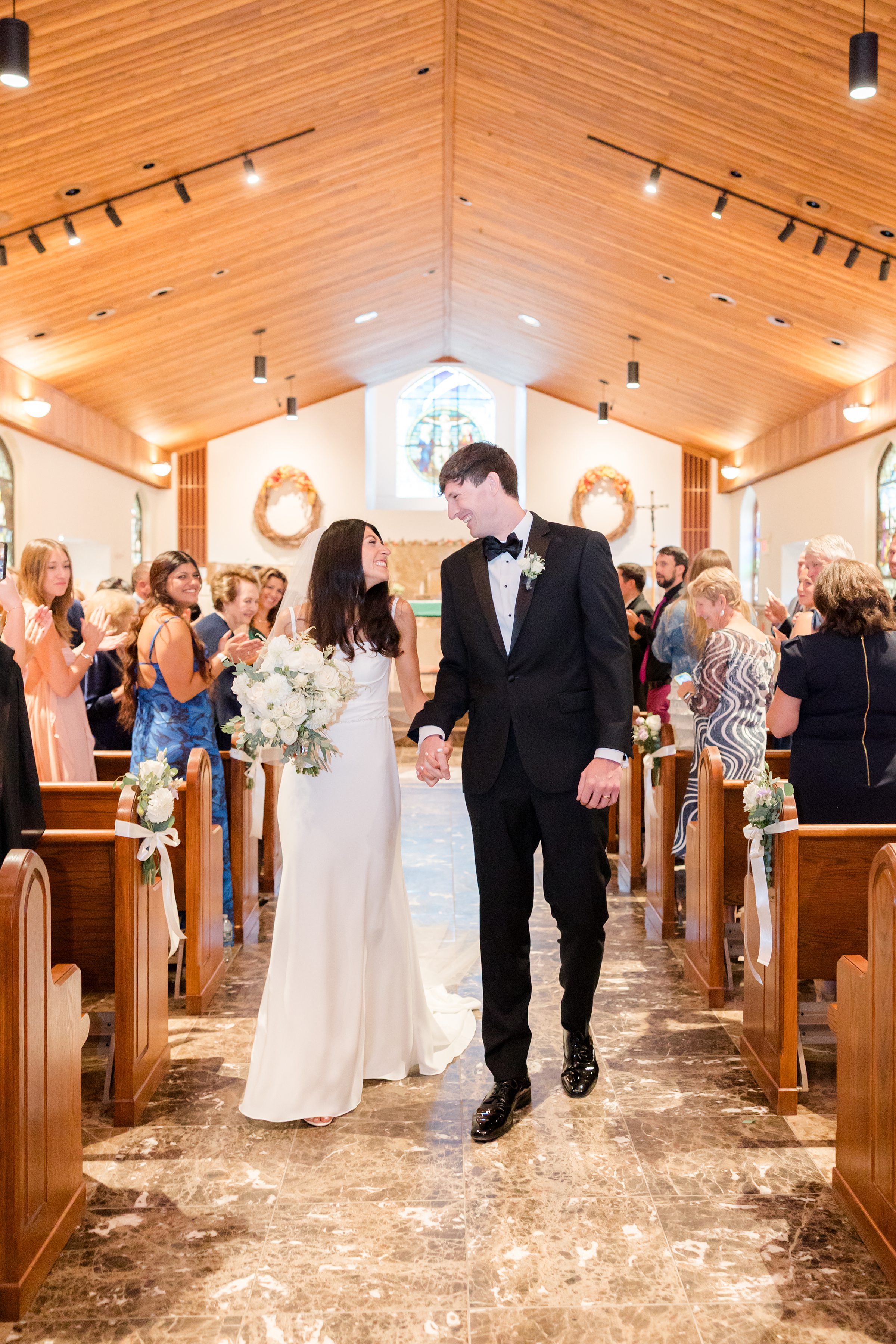 Beneath soft light and sacred stillness, the bride and groom share a tender kiss, beginning their forever.
