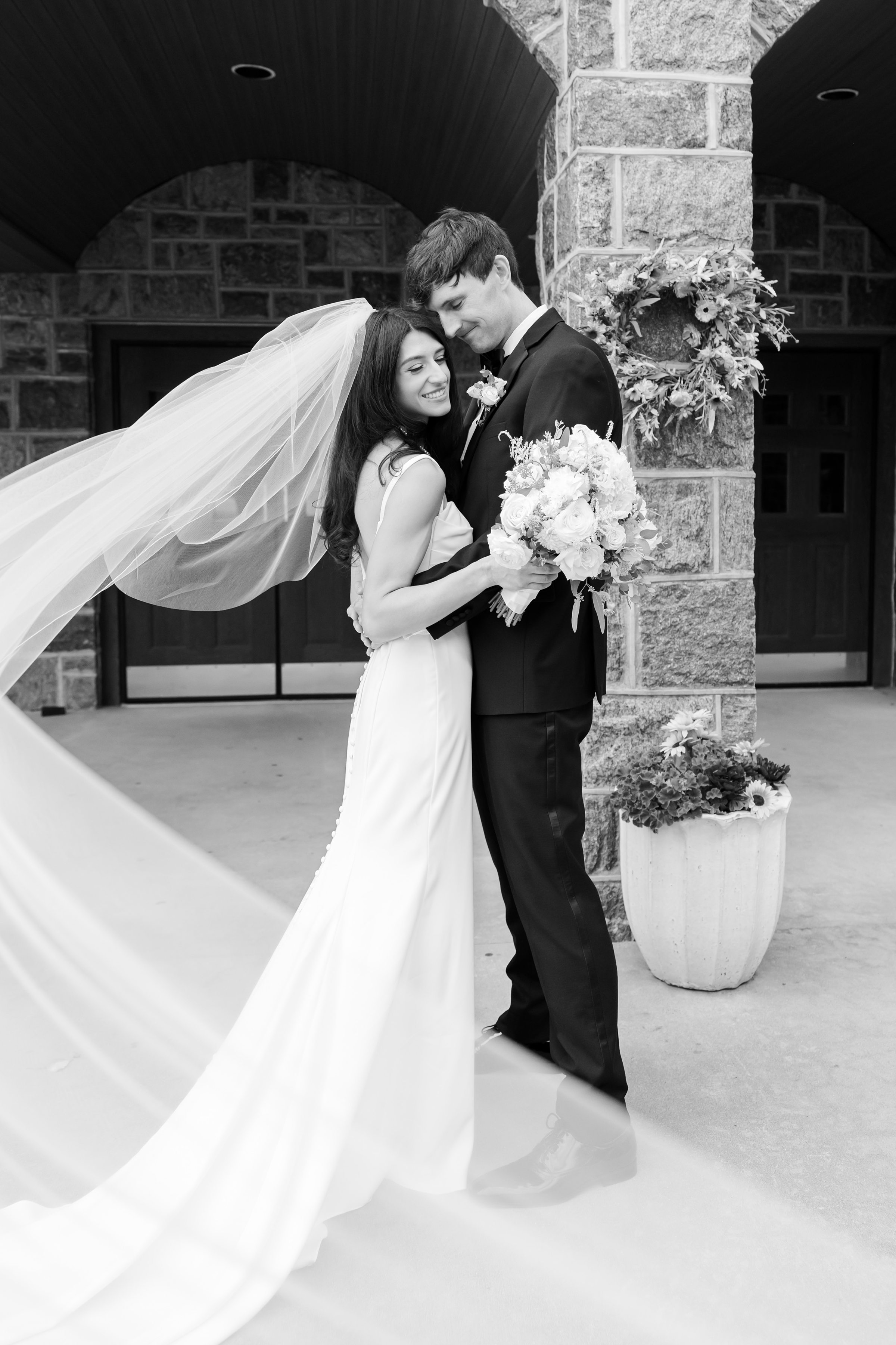 Groom gently holds his bride close as she leans into him with a soft smile, their love calm, steady, and deeply felt