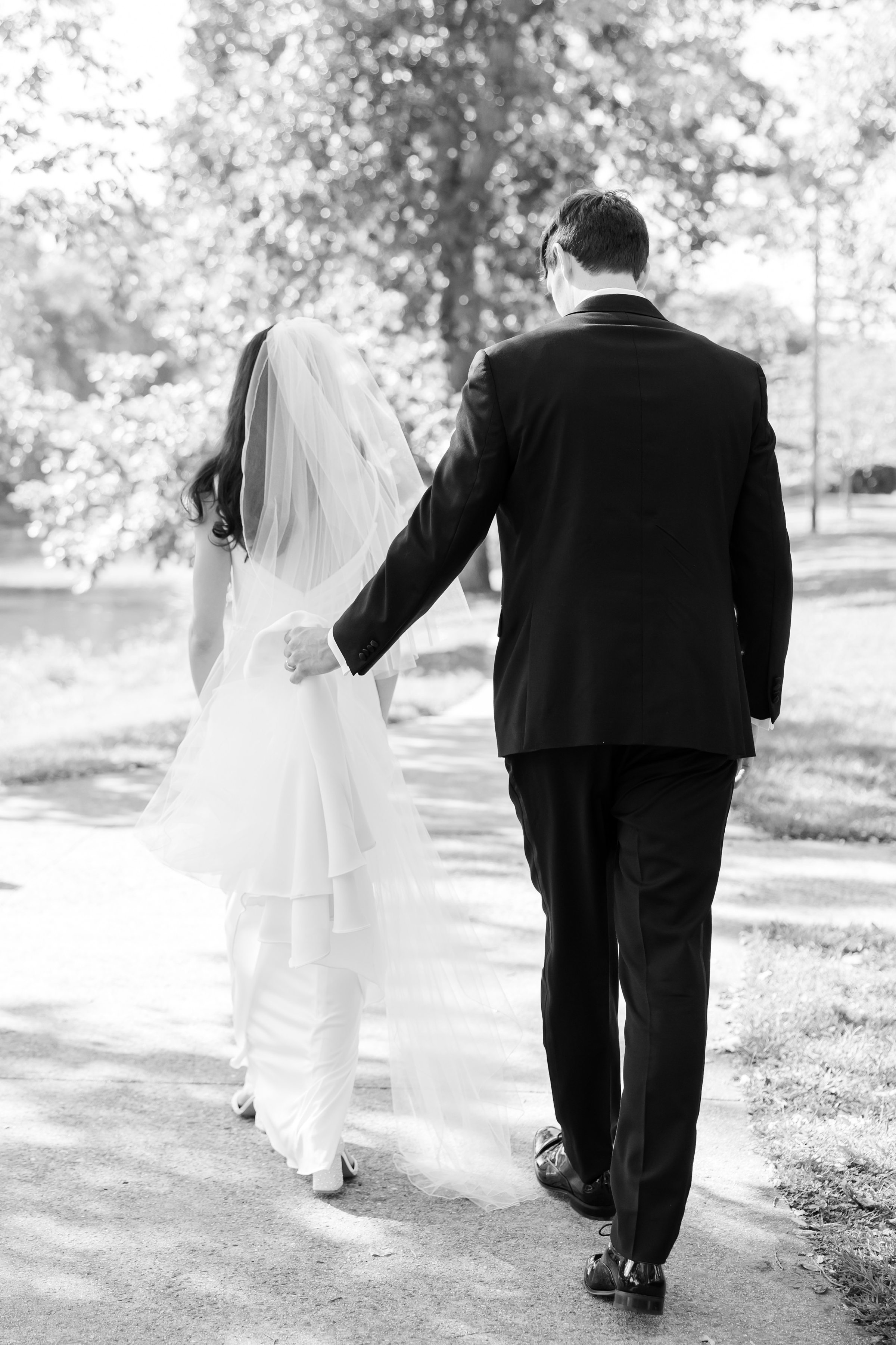Groom guides his bride forward with a gentle touch, their steps in perfect harmony as they walk into forever.