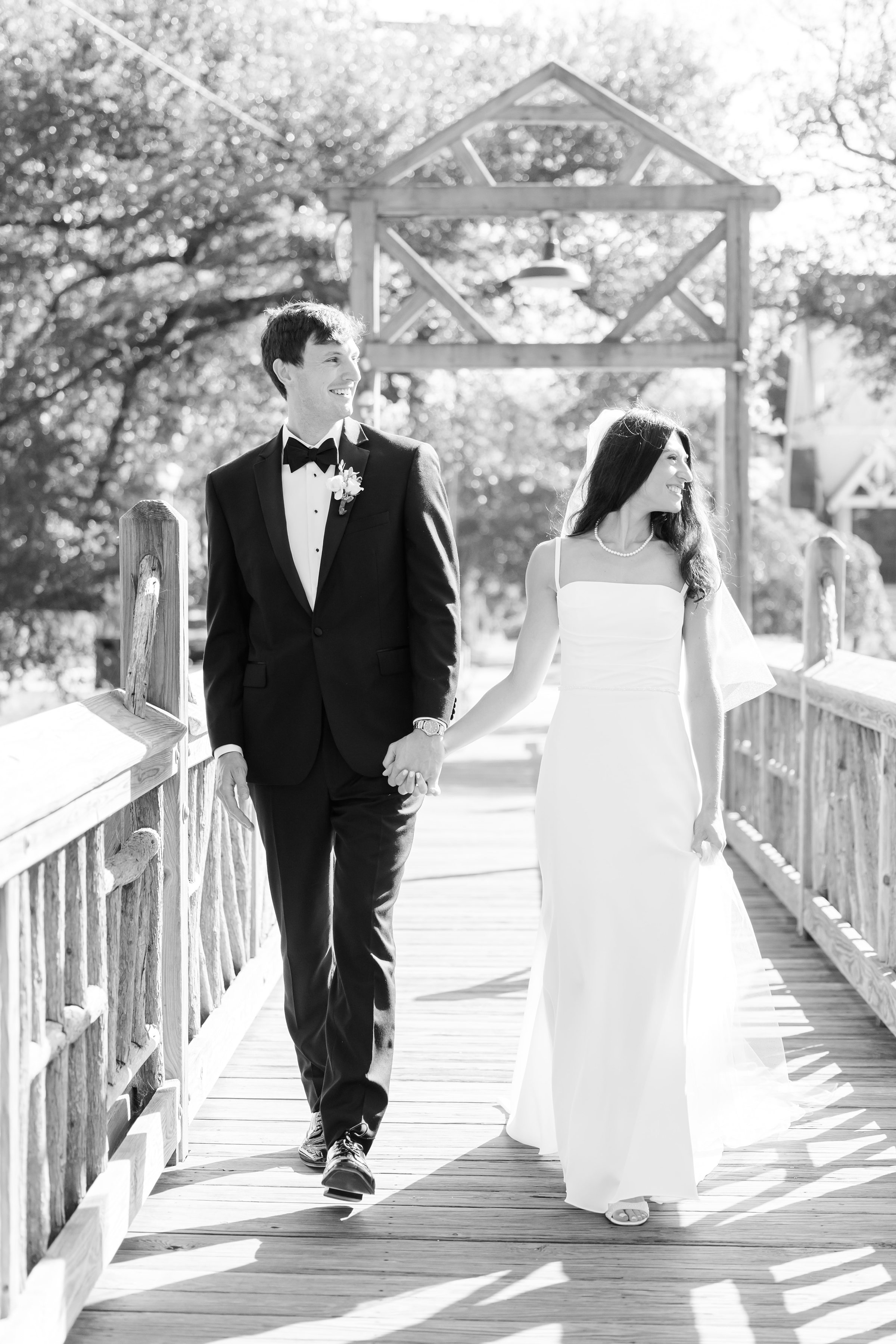 Groom glances ahead while the bride looks on with a soft smile, their hands intertwined in a moment of calm, enduring love.