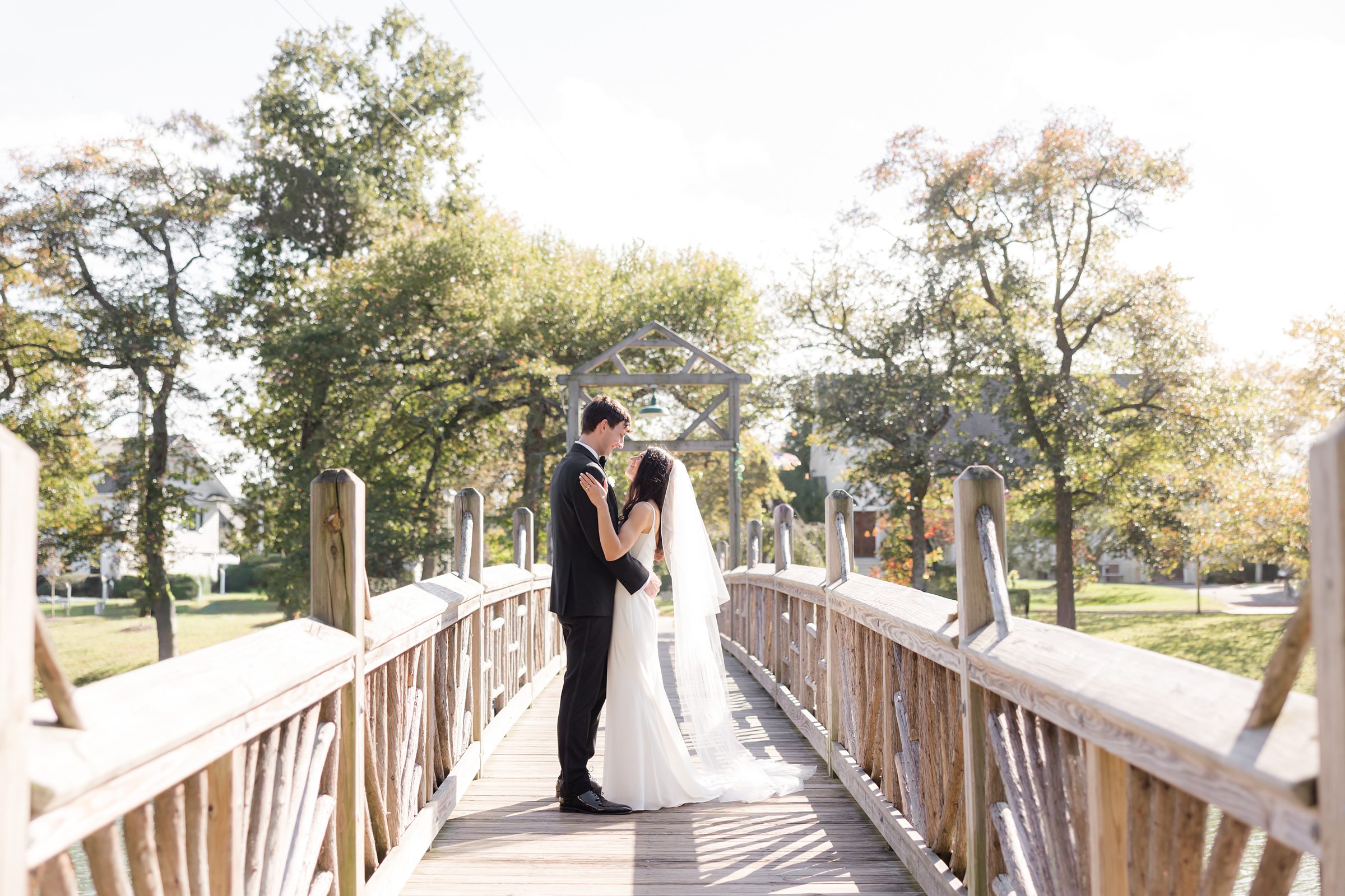 Bride and groom gently hold one another on a wooden bridge, their love calm, steady, and beautifully present.