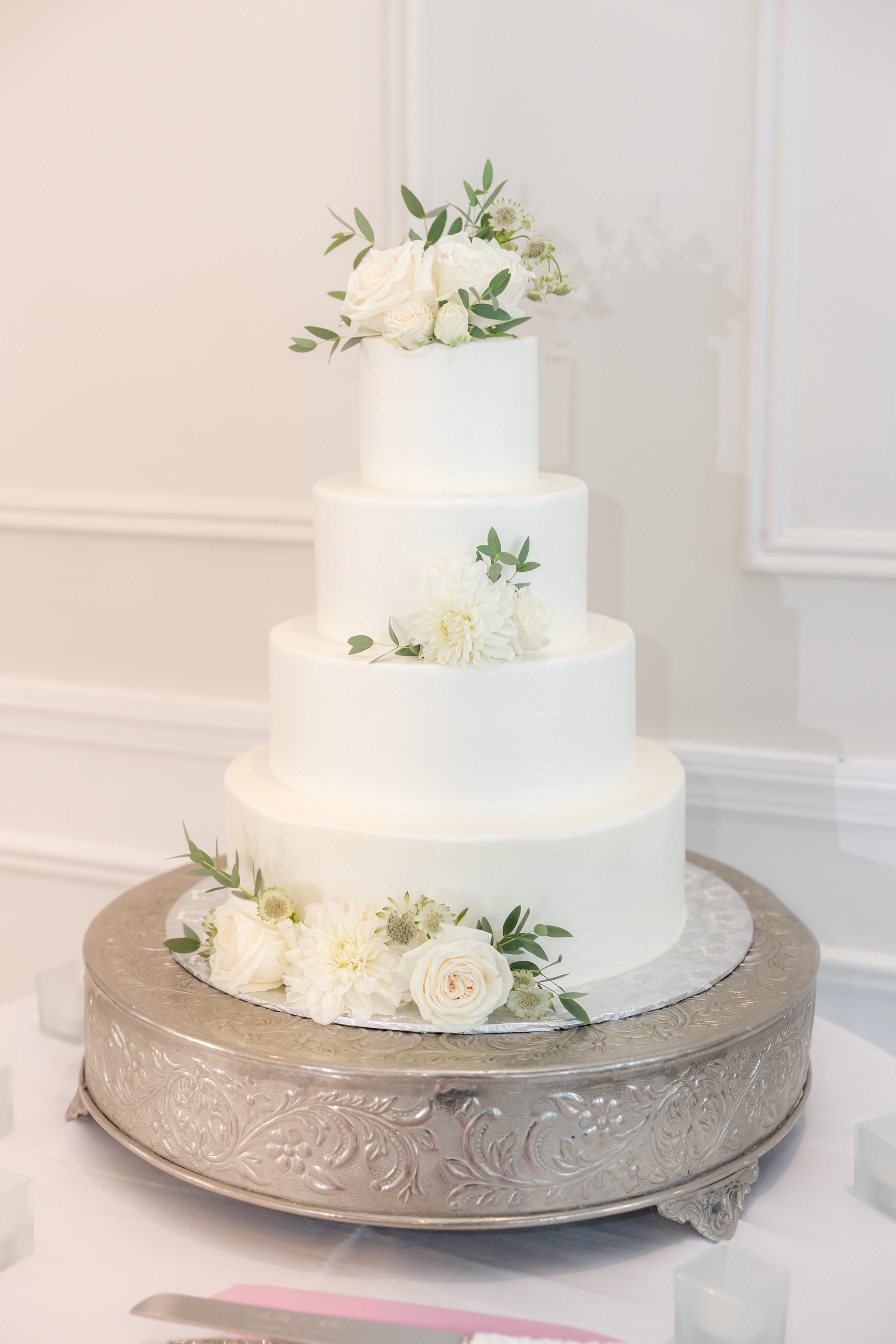 Classic white wedding cake adorned with fresh blooms stands beautifully, symbolizing the sweetness and elegance of the couple’s union.
