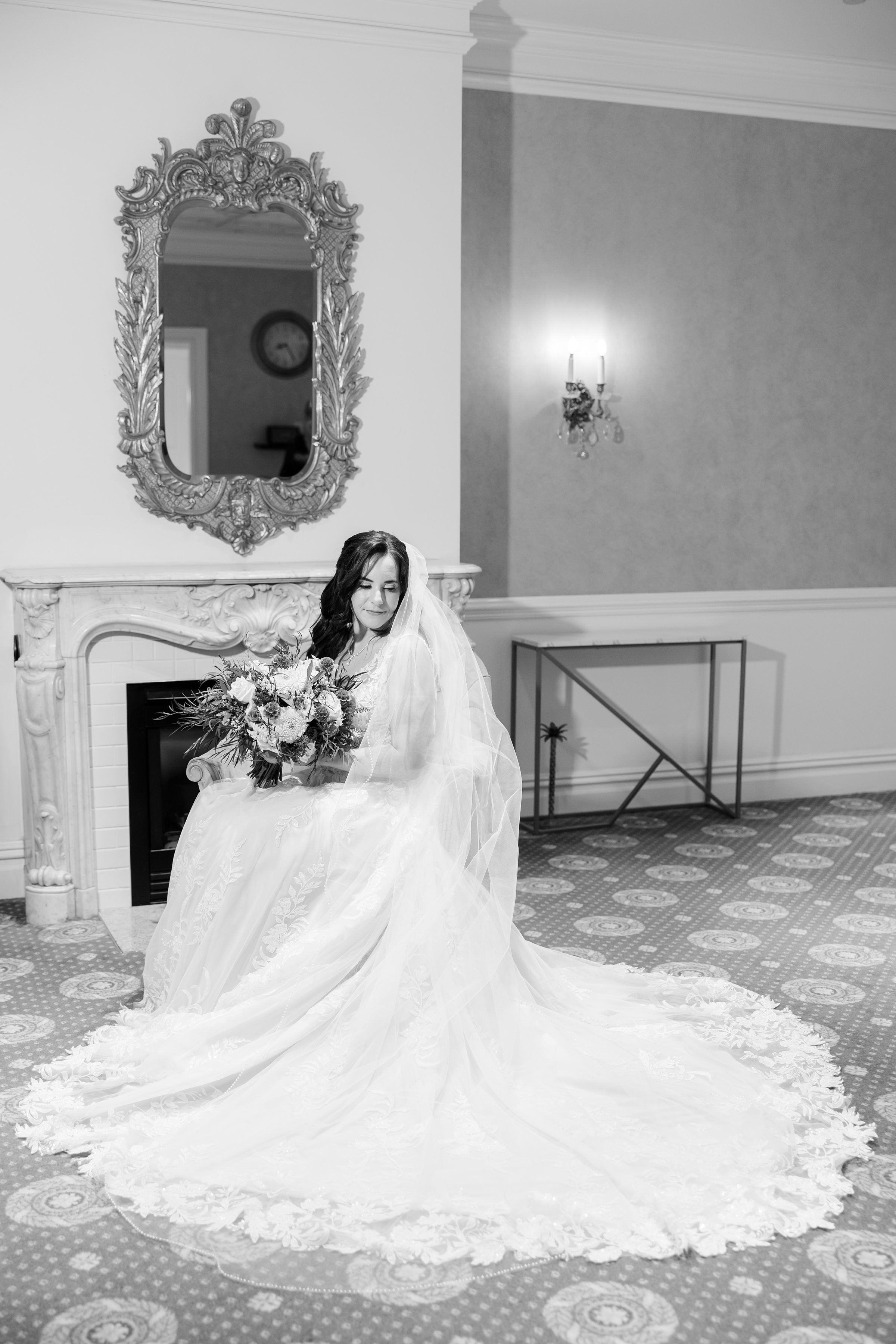 Bride seated with her bouquet in an elegant room.