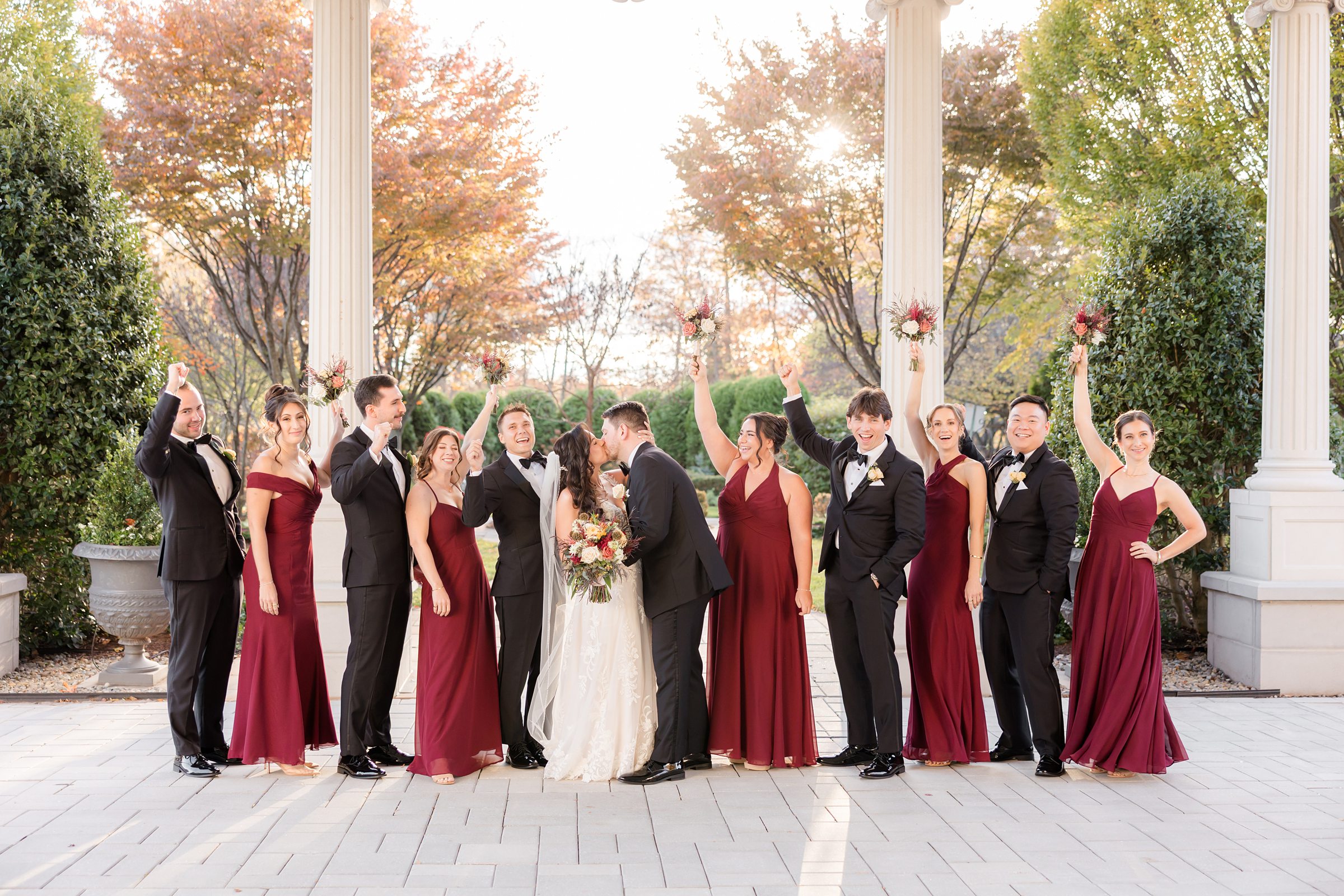 Wedding party cheers as the couple shares a kiss, capturing a lively and heartfelt moment of unity