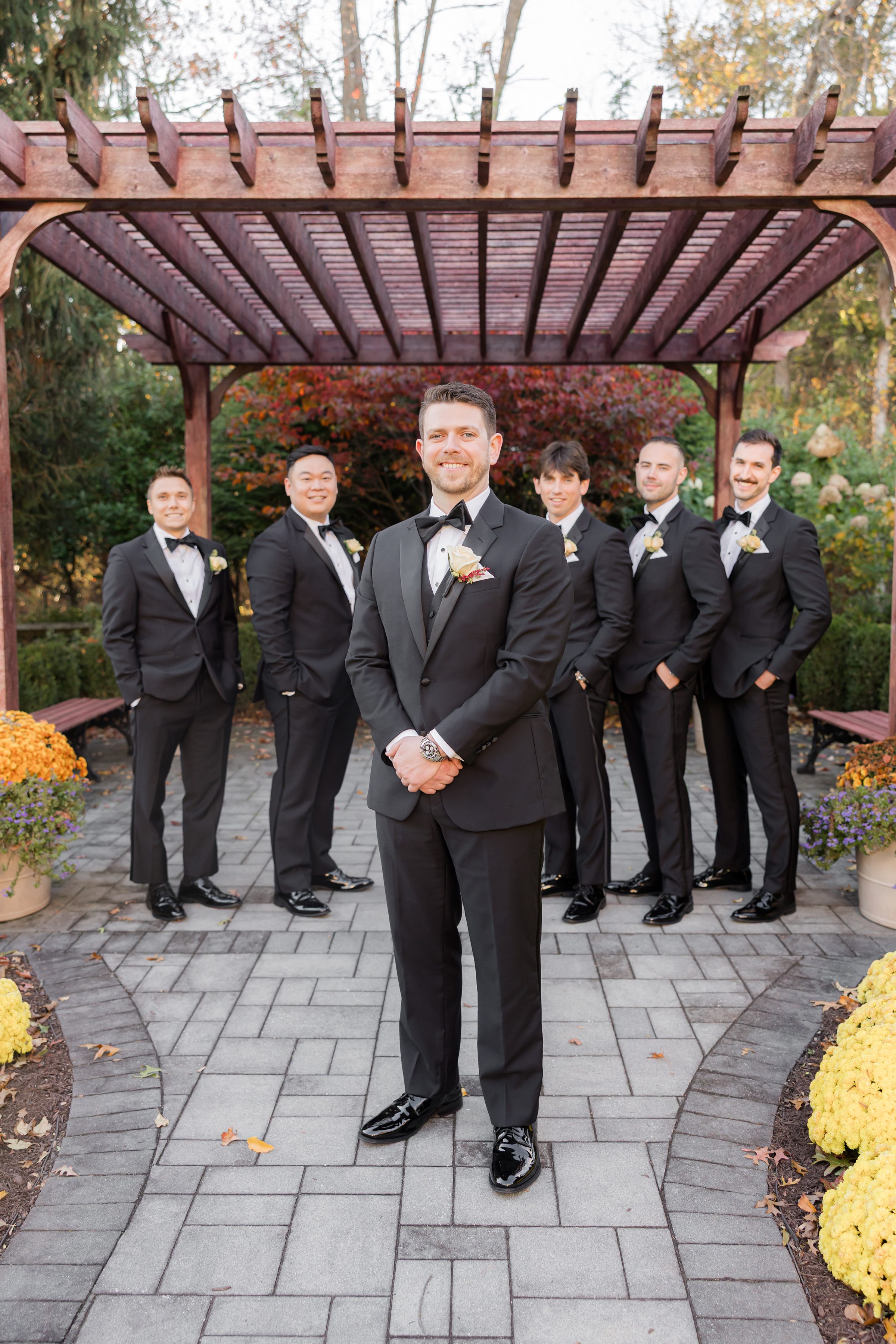 Groom stands with his groomsmen, smiling proudly, surrounded by friendship and anticipation before the ceremony.