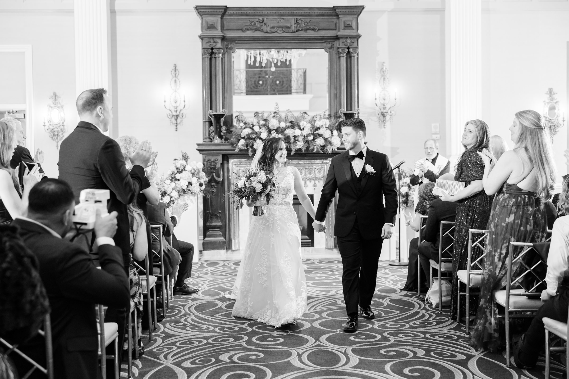 Bride and groom walk together down the aisle, smiling as loved ones celebrate their newly married joy