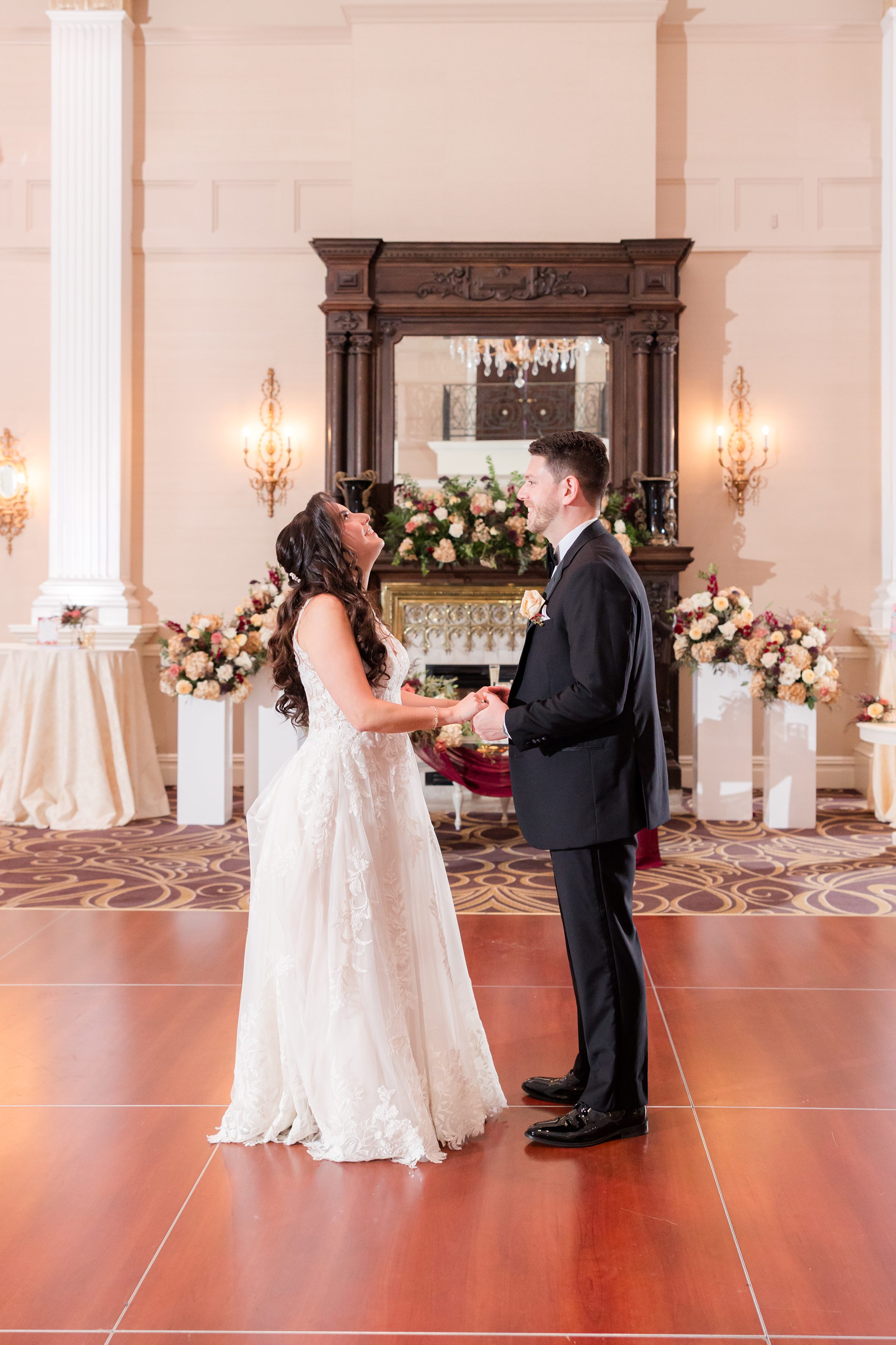 Bride and groom hold hands and gaze at each other with pure love, sharing a quiet, romantic moment on the dance floor
