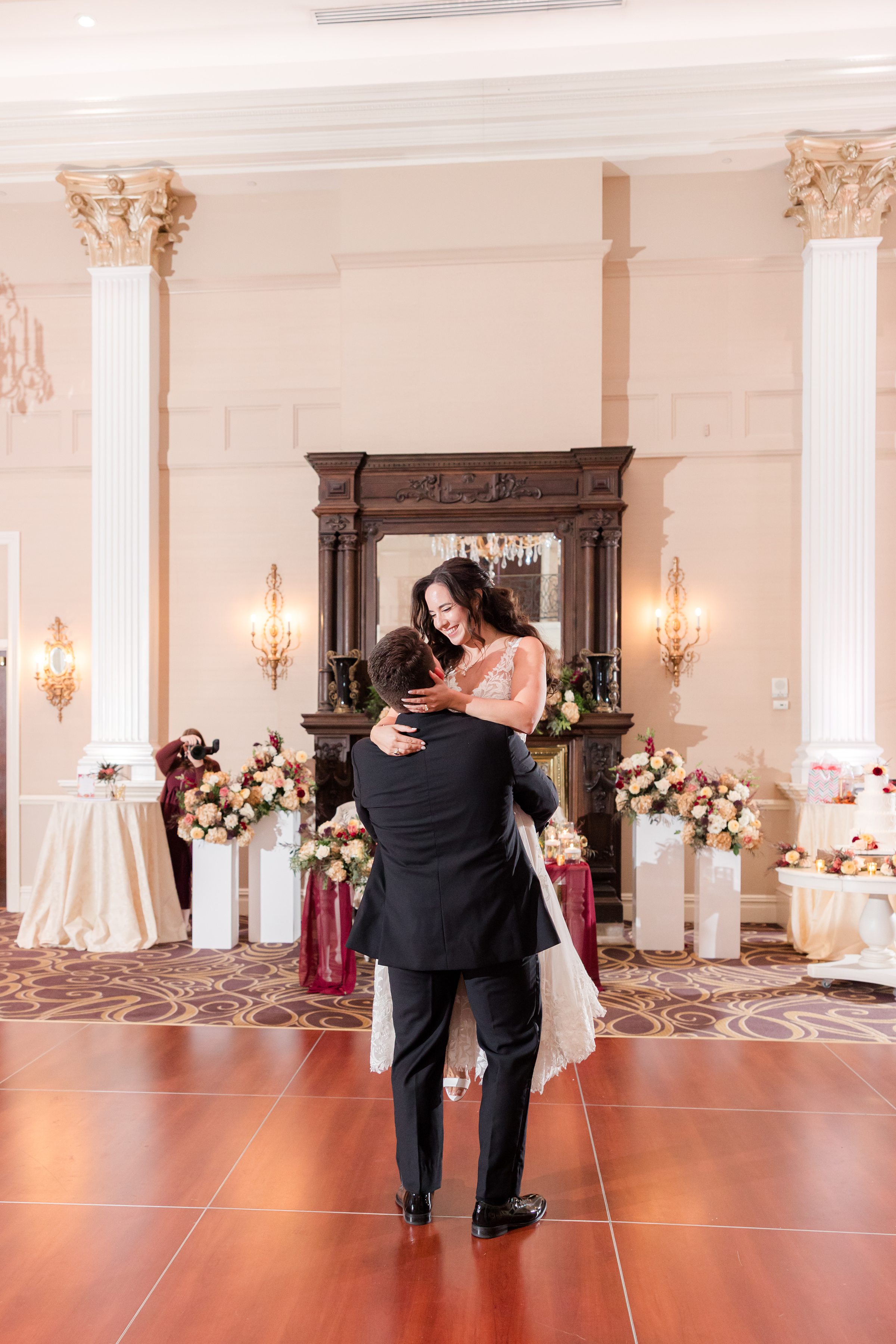 Groom lifts the bride into his arms as she smiles down at him, sharing a joyful and romantic moment on the dance floor
