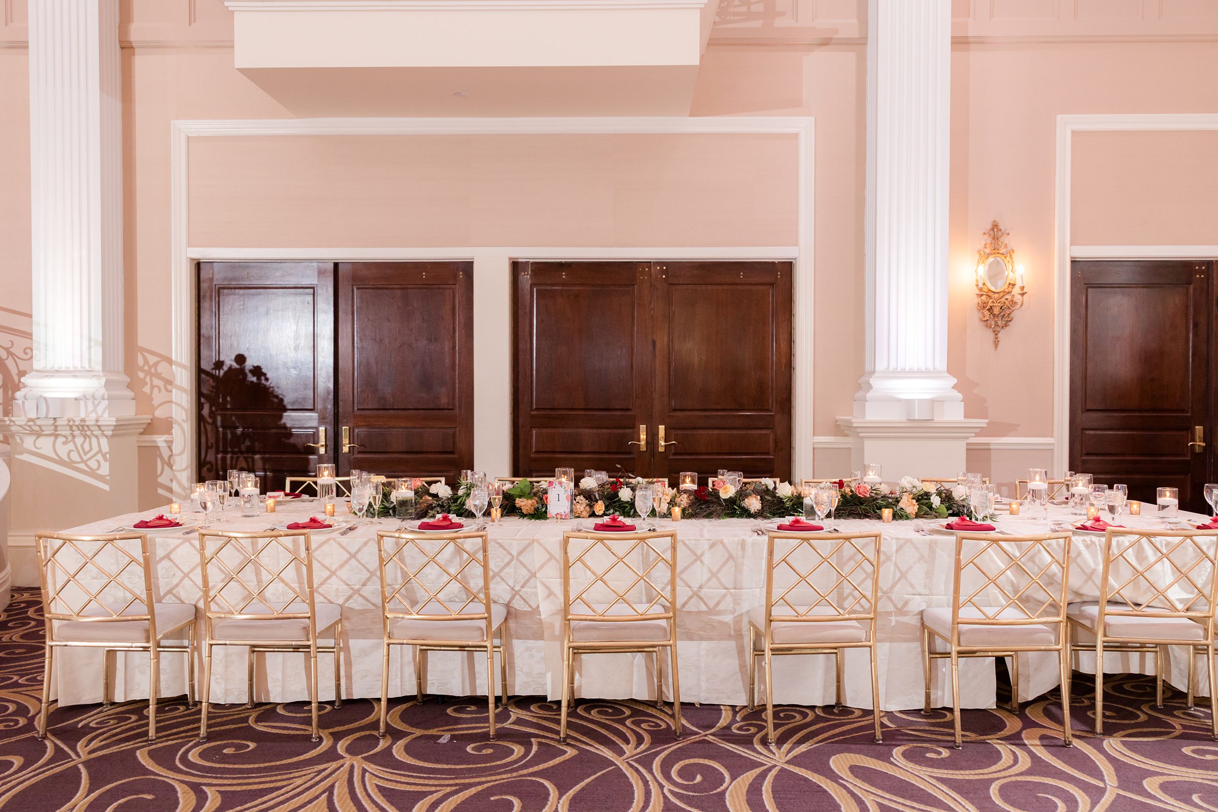 Beautifully styled sweetheart table framed by lush florals and soft drapery, set for an intimate newlywed moment