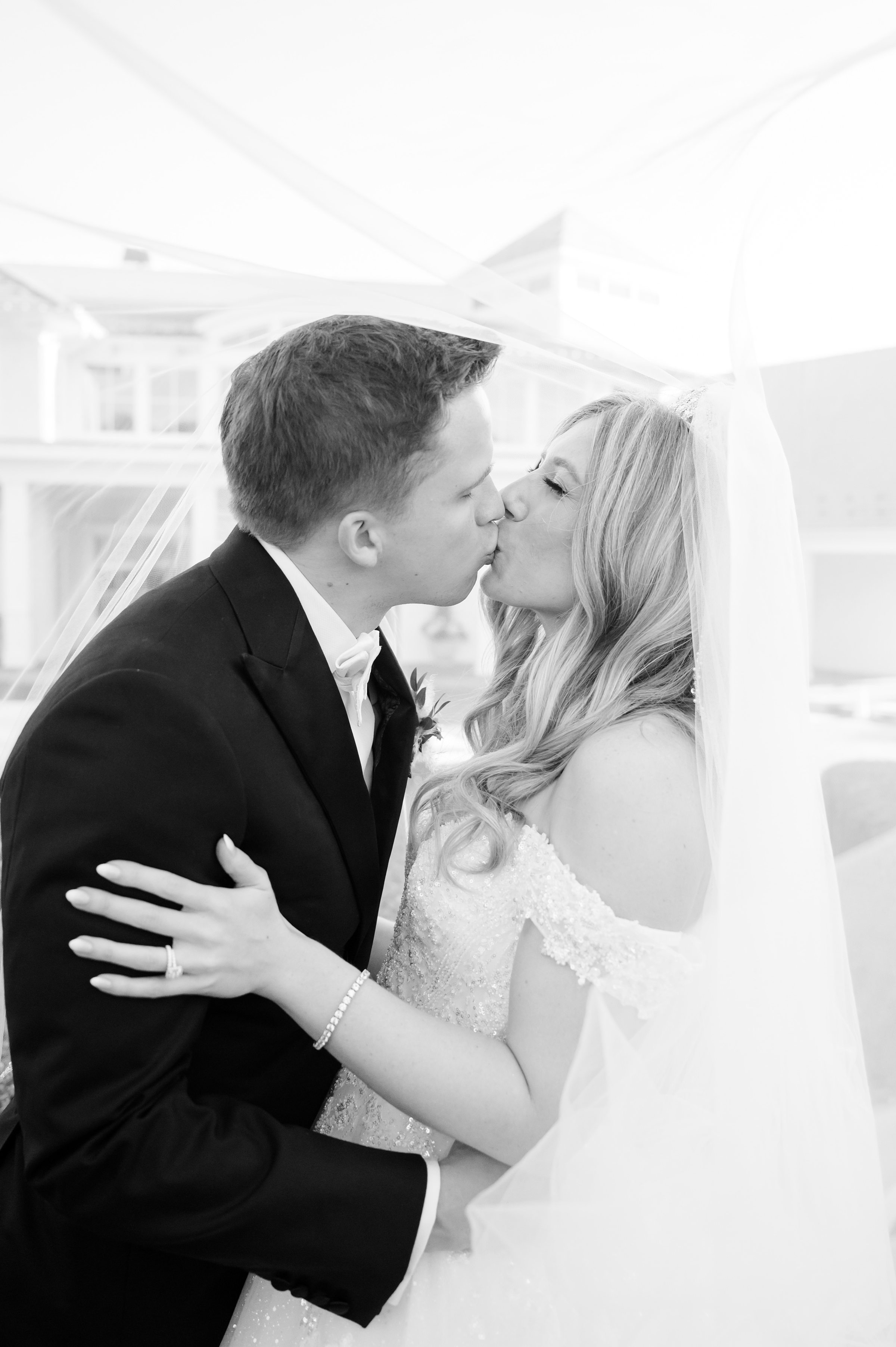 Bride and groom sharing a soft kiss beneath the bride’s veil.