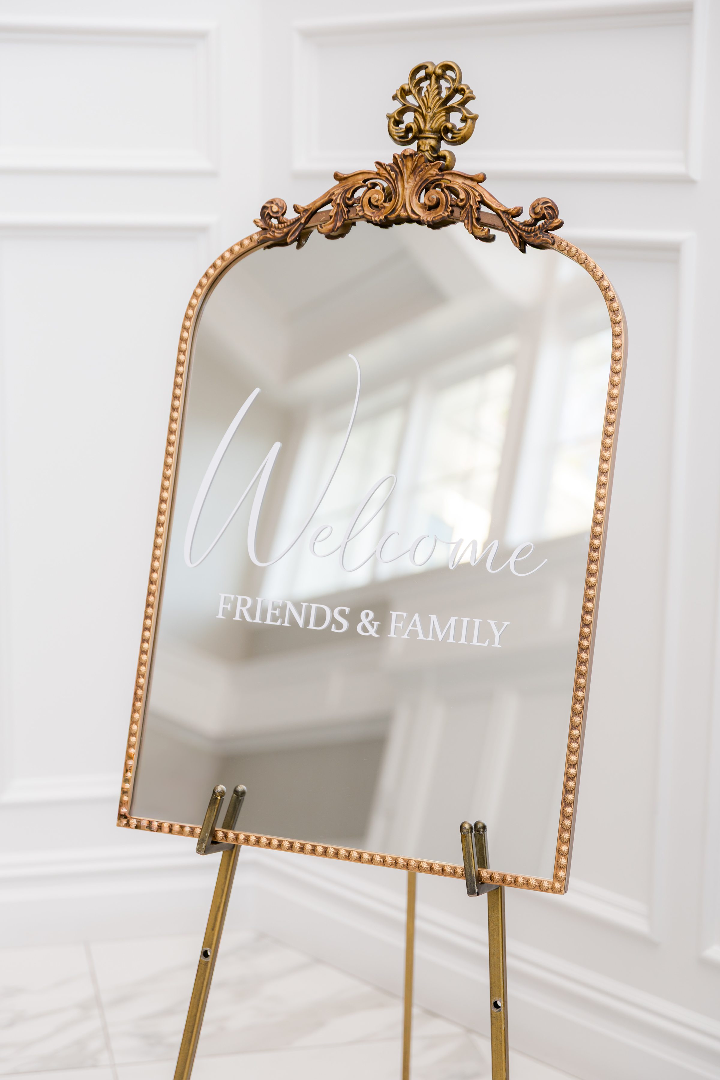 Gold framed mirror sign welcoming friends and family with a soft, romantic glow.