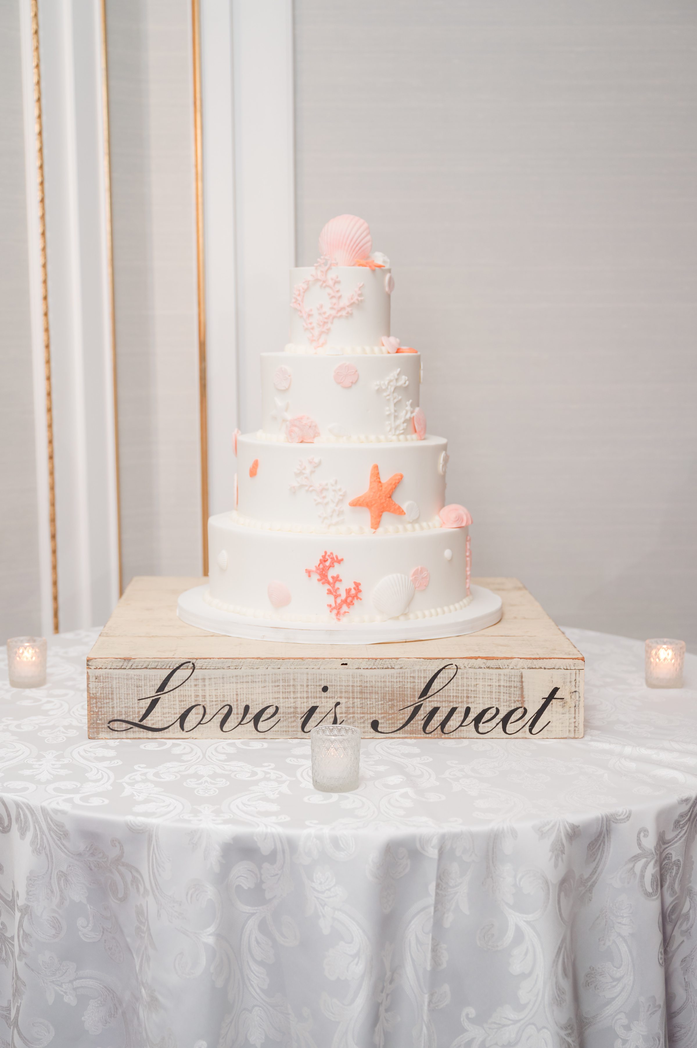 White tiered wedding cake with coral and seashell decorations 