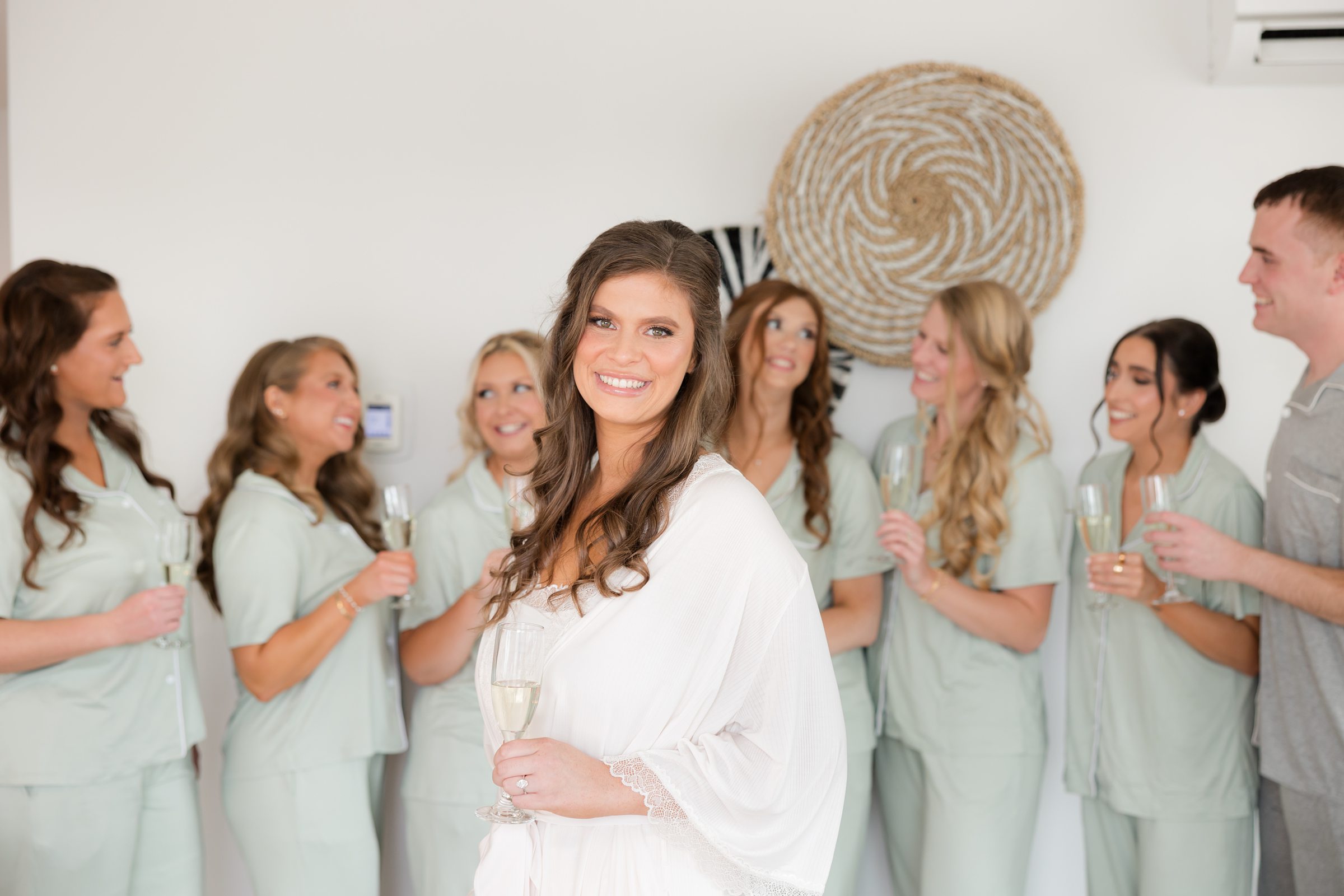 Bride centered with bridesmaids around her, all holding champagne and smiling.