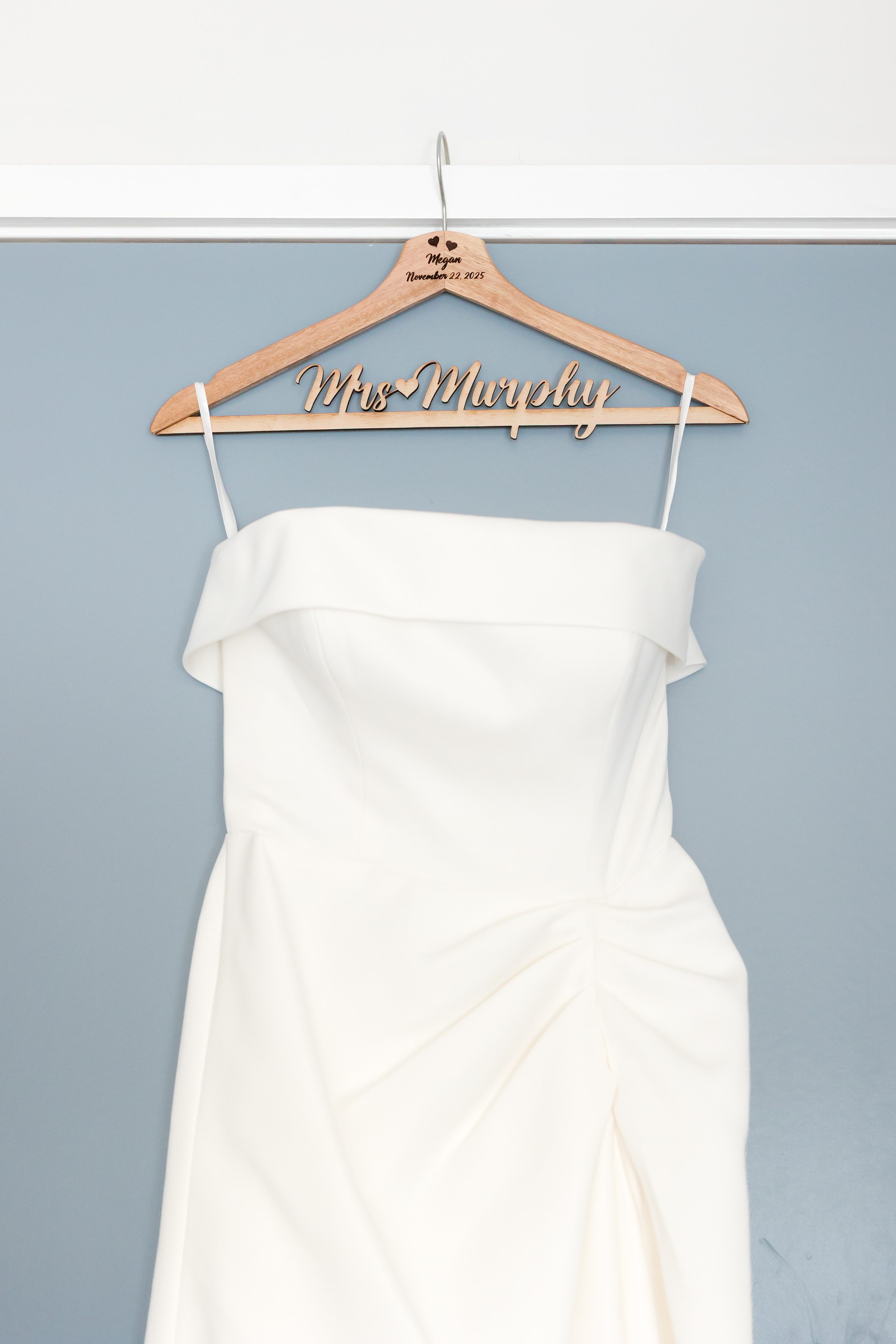 Wedding dress hanging on a personalized hanger reading “Mrs. Murphy.”