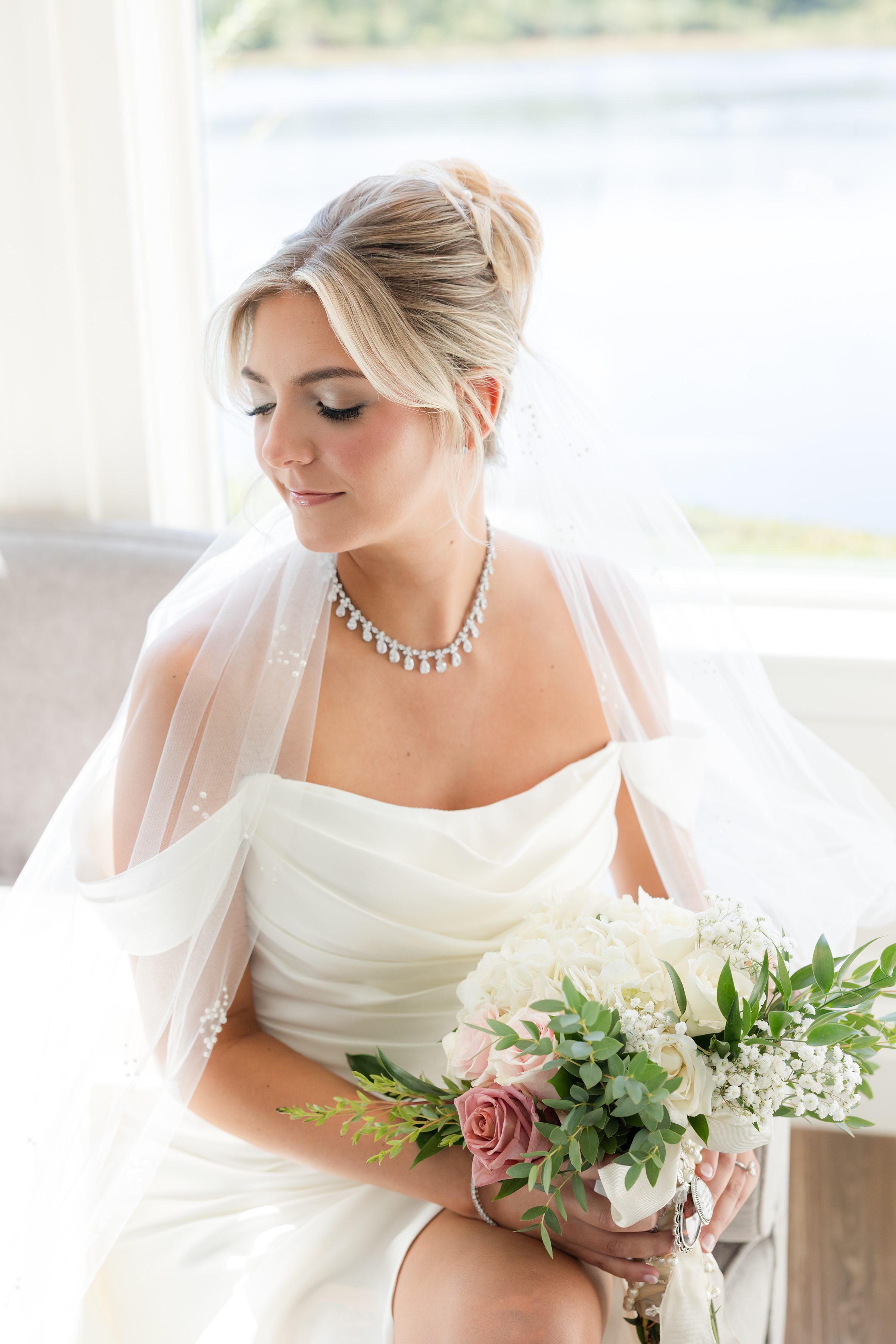 Bride holding her bouquet, her soft expression and delicate jewelry adding an intimate, romantic feel.