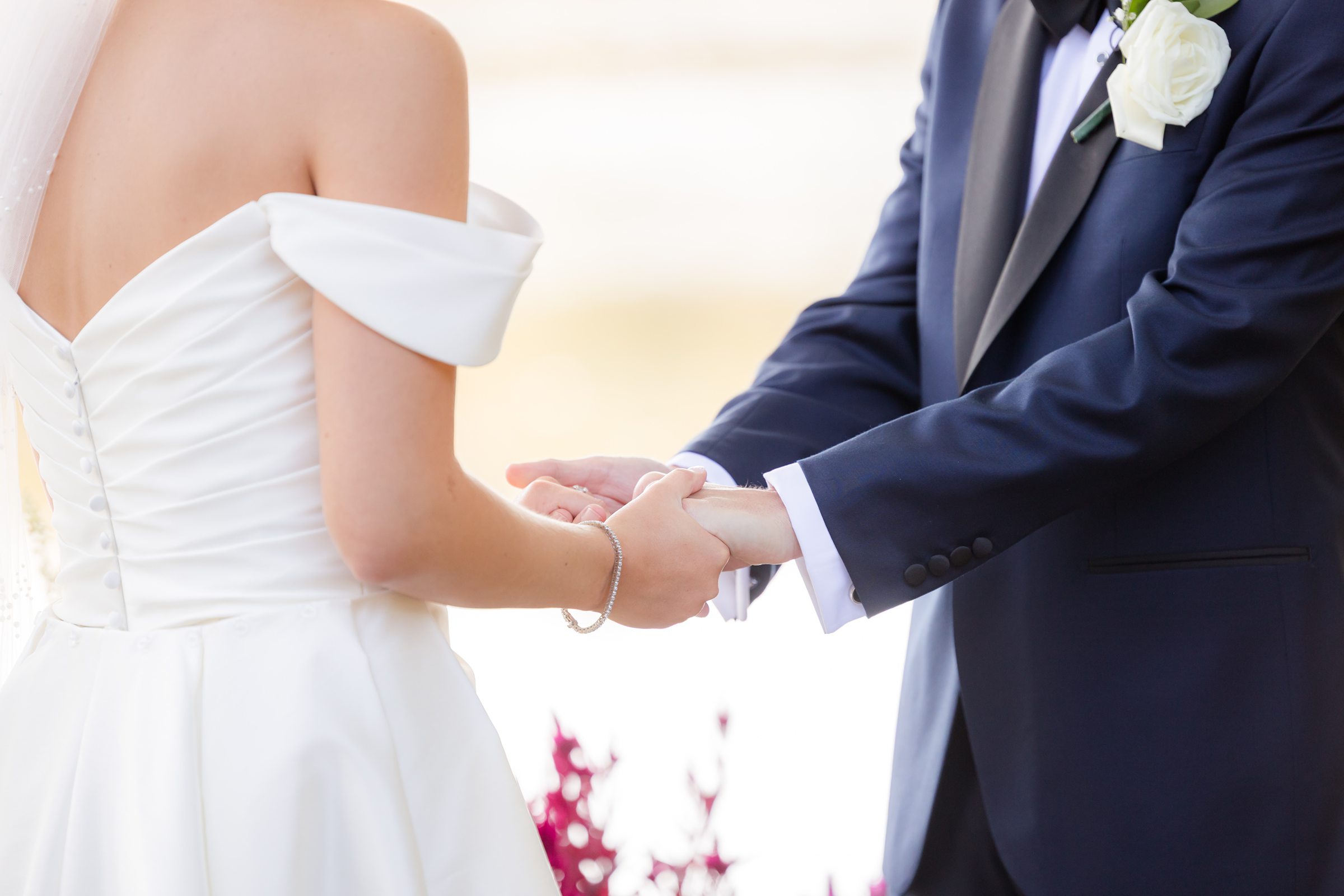 Bride and groom holding hands, symbolizing love and connection.