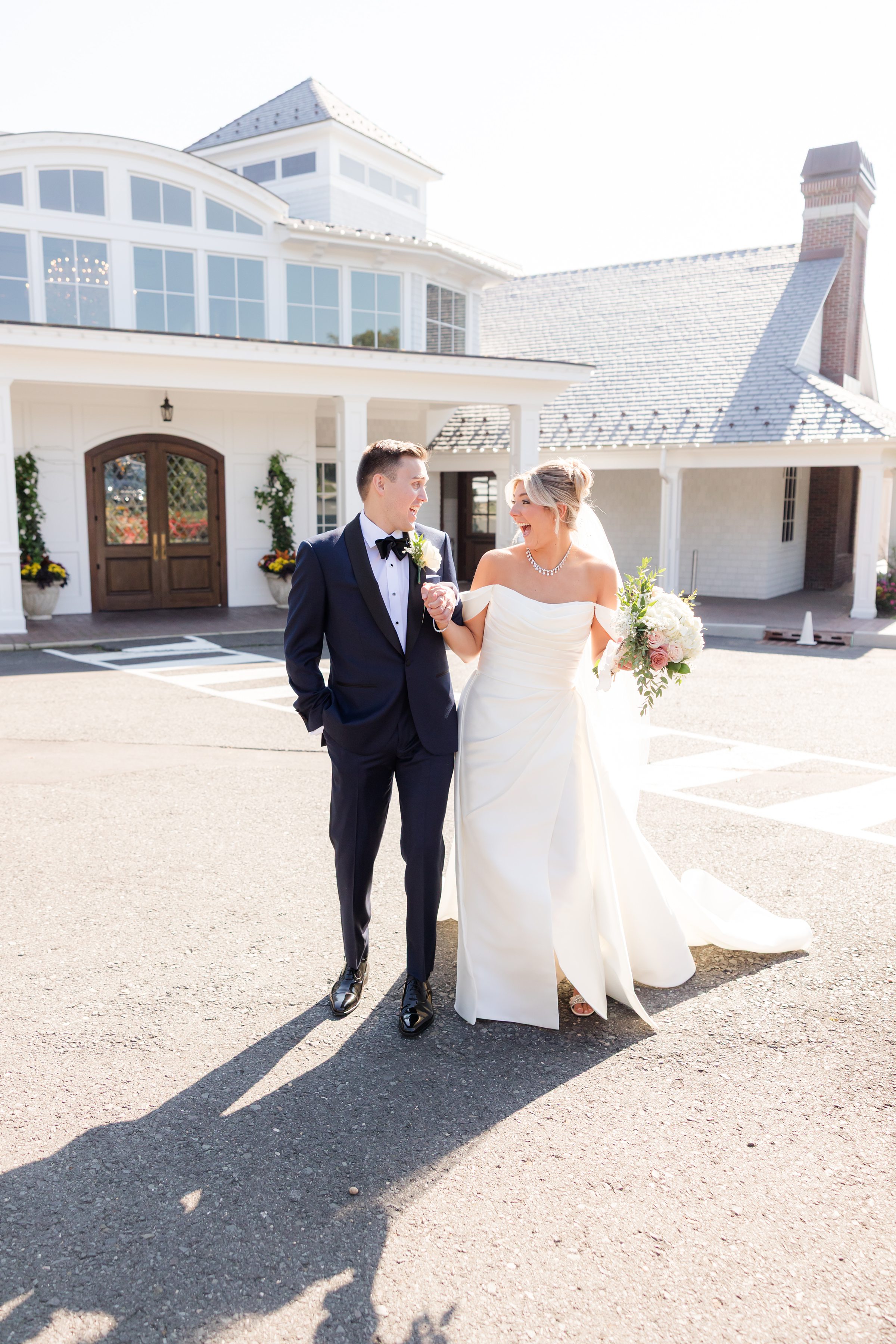 Newlyweds together, smiling brightly outside a sunlit venue.