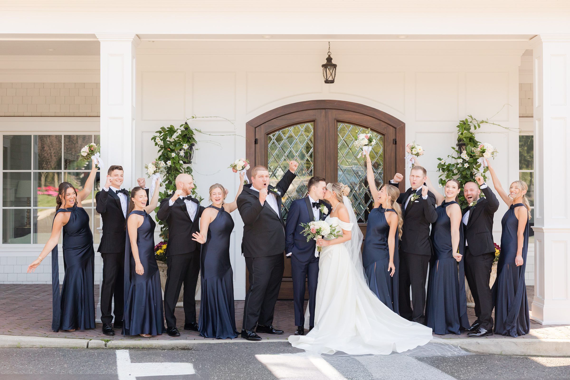 Bride and groom exit the venue together as friends cheer and raise bouquets in celebration.