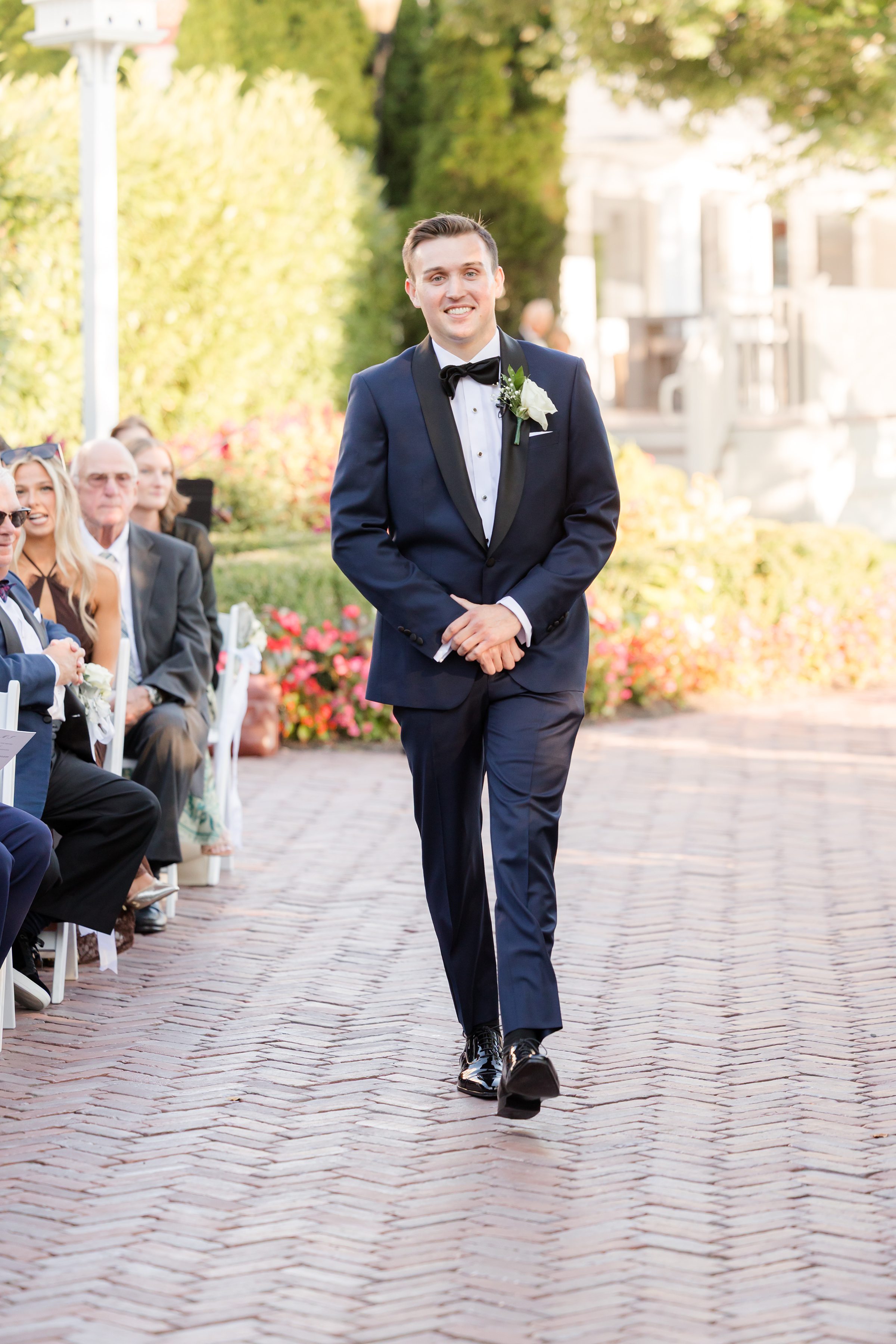 Groom walks down the aisle toward the ceremony, smiling with anticipation.