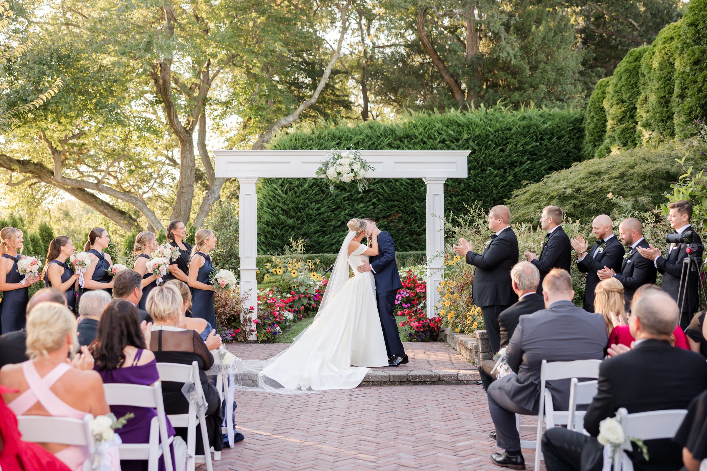 Bride and groom share a kiss down the aisle surrounded by guests during an outdoor garden ceremony
