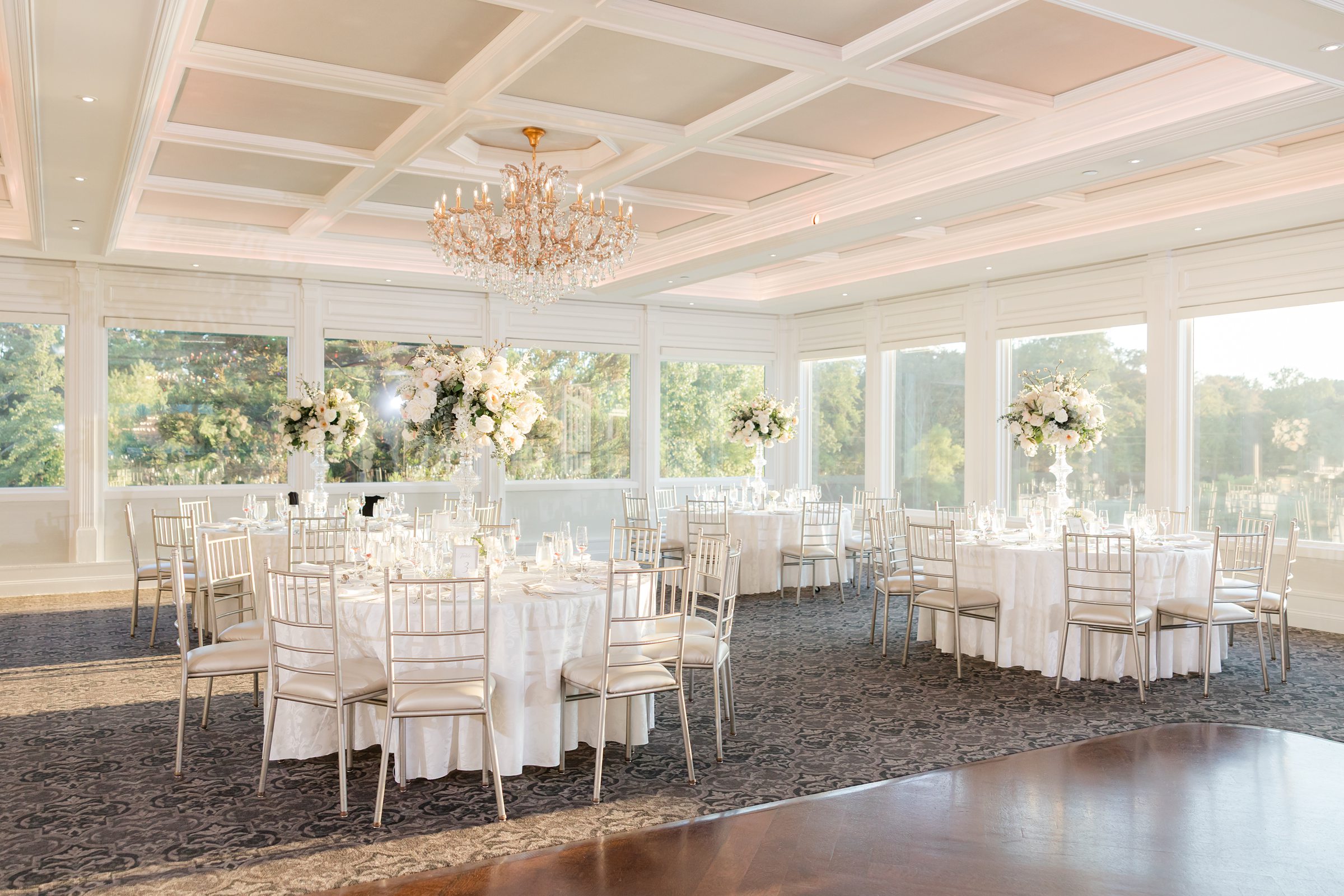Wedding reception space is filled with natural light and soft floral arrangements, creating a serene and romantic atmosphere for the celebration.