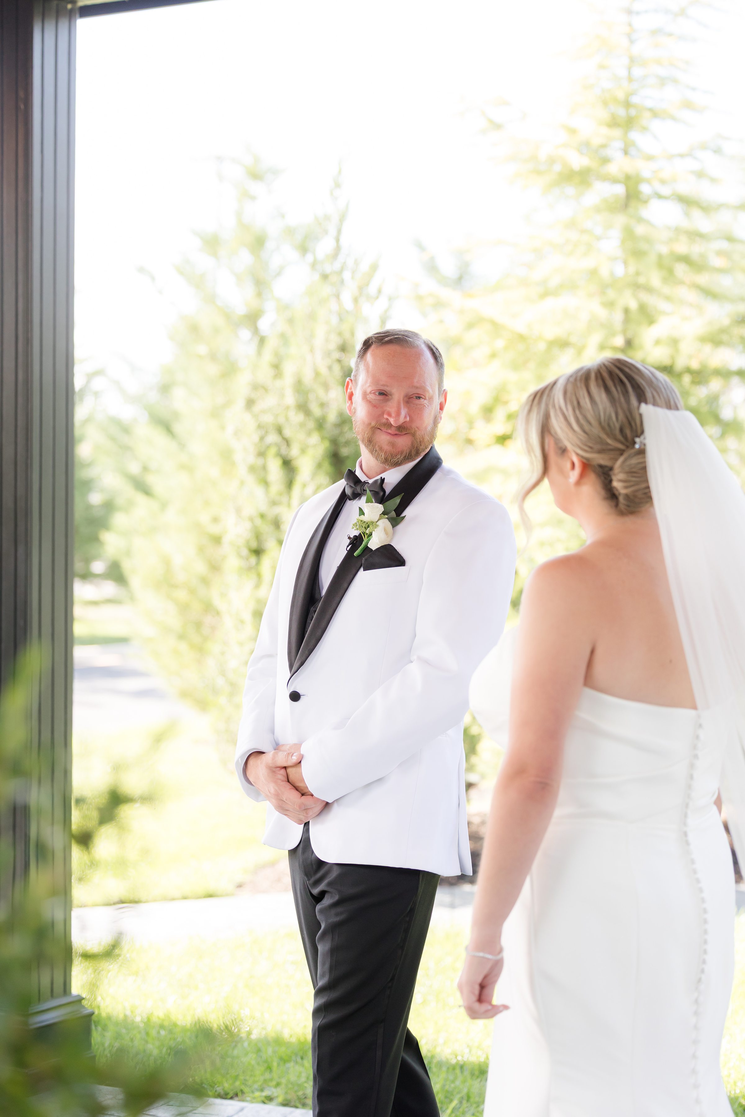 Groom smiles warmly as he turns to see his bride approaching, a tender first-look moment filled with anticipation and love