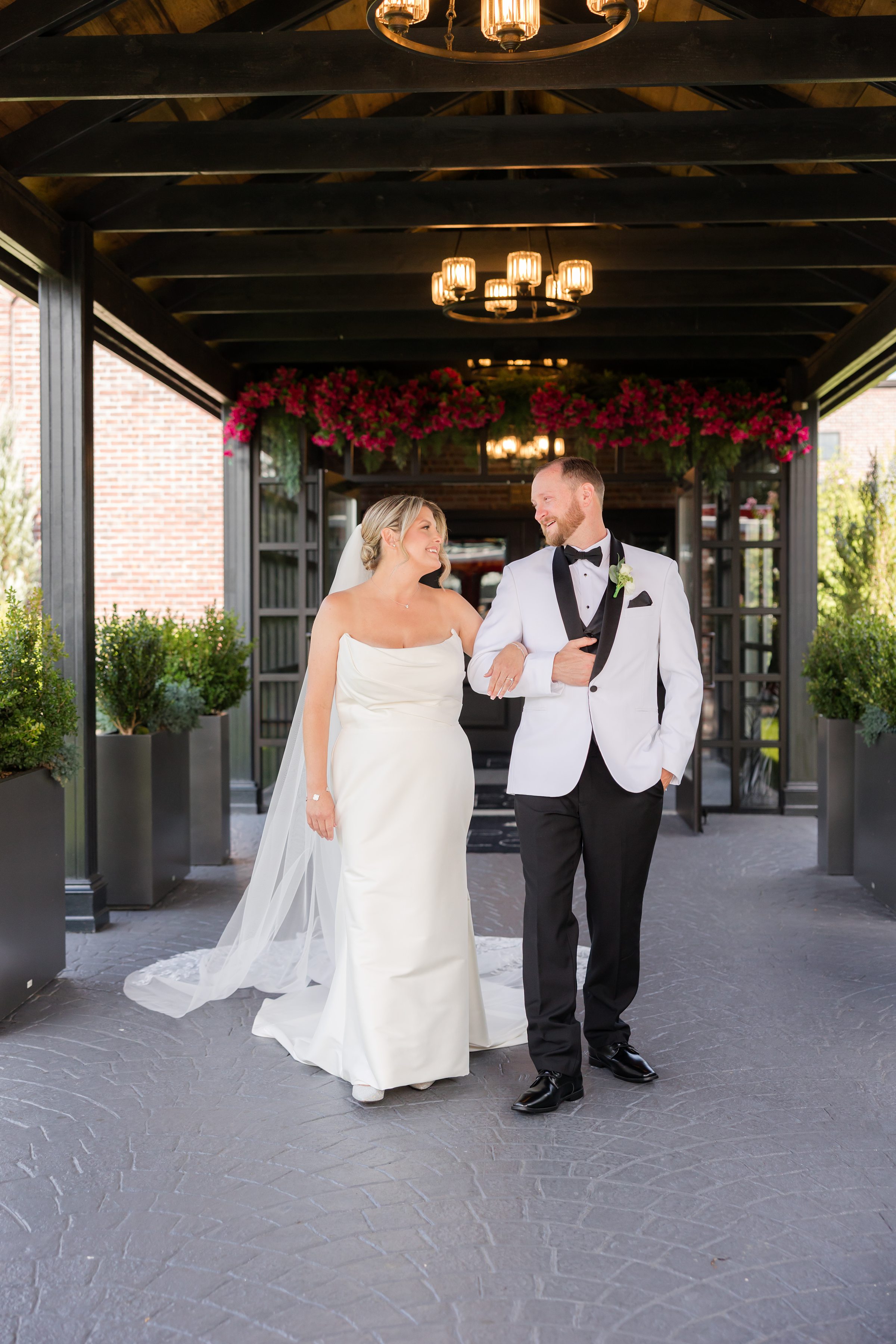 Bride and groom walk arm in arm beneath a covered walkway, savoring their first moments as husband and wife