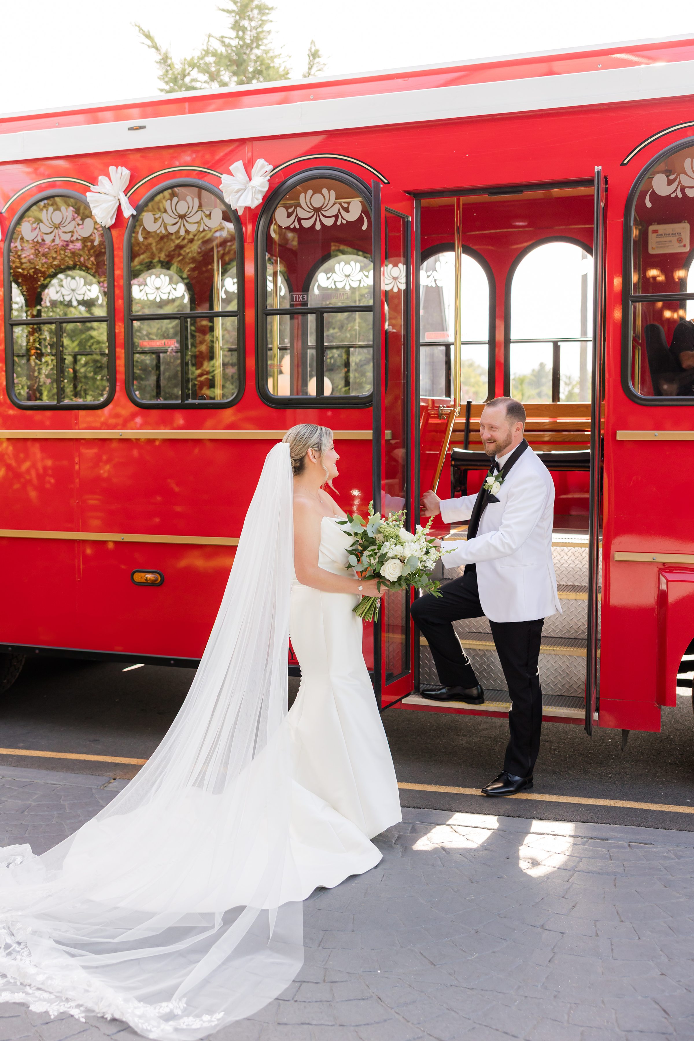 Groom helps his bride step onto the trolley, a playful and loving gesture
