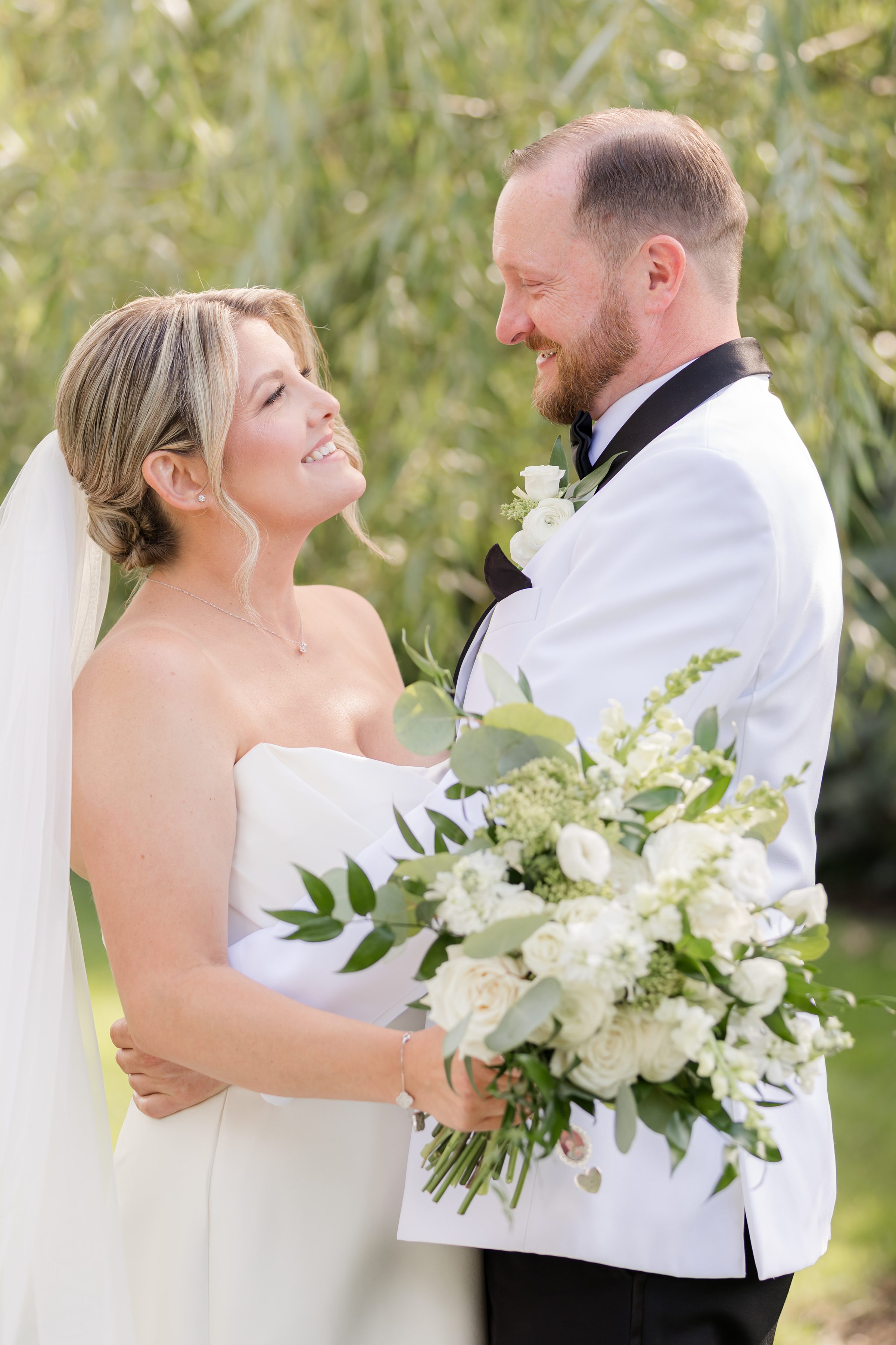 Bride and groom gaze into each other’s eyes, wrapped in quiet love beneath the trees