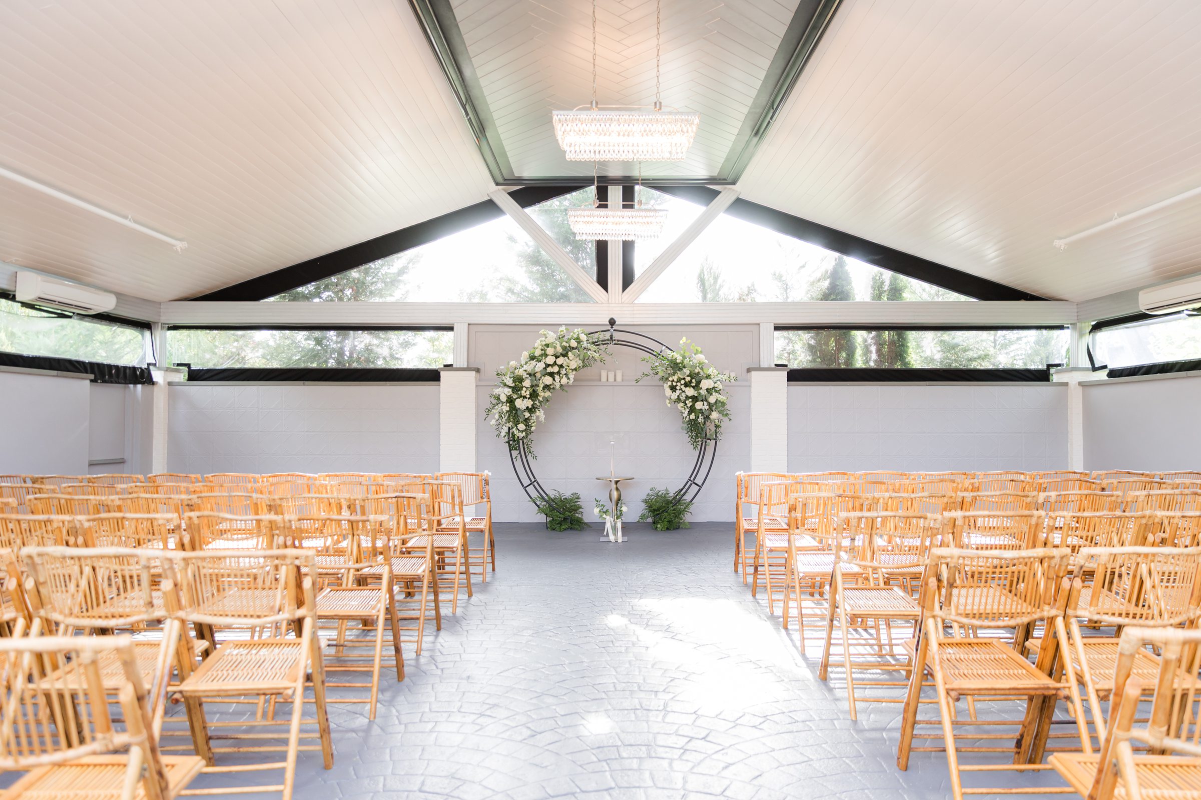 Sunlit ceremony space with rows of chairs leading to a dreamy floral arch, ready for “I do.”