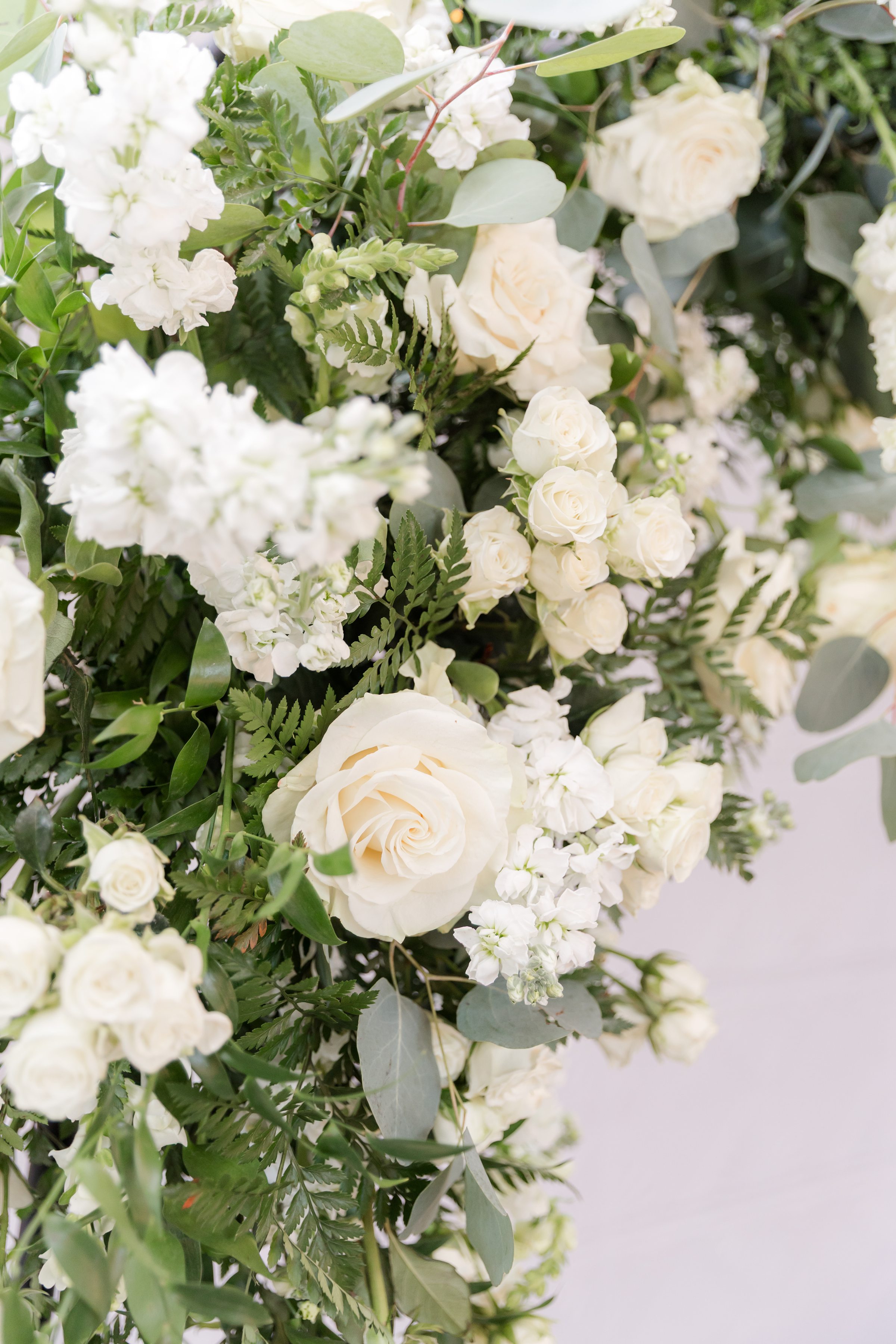 Elegant white roses and greenery intertwine in a romantic floral arrangement, soft and timeless