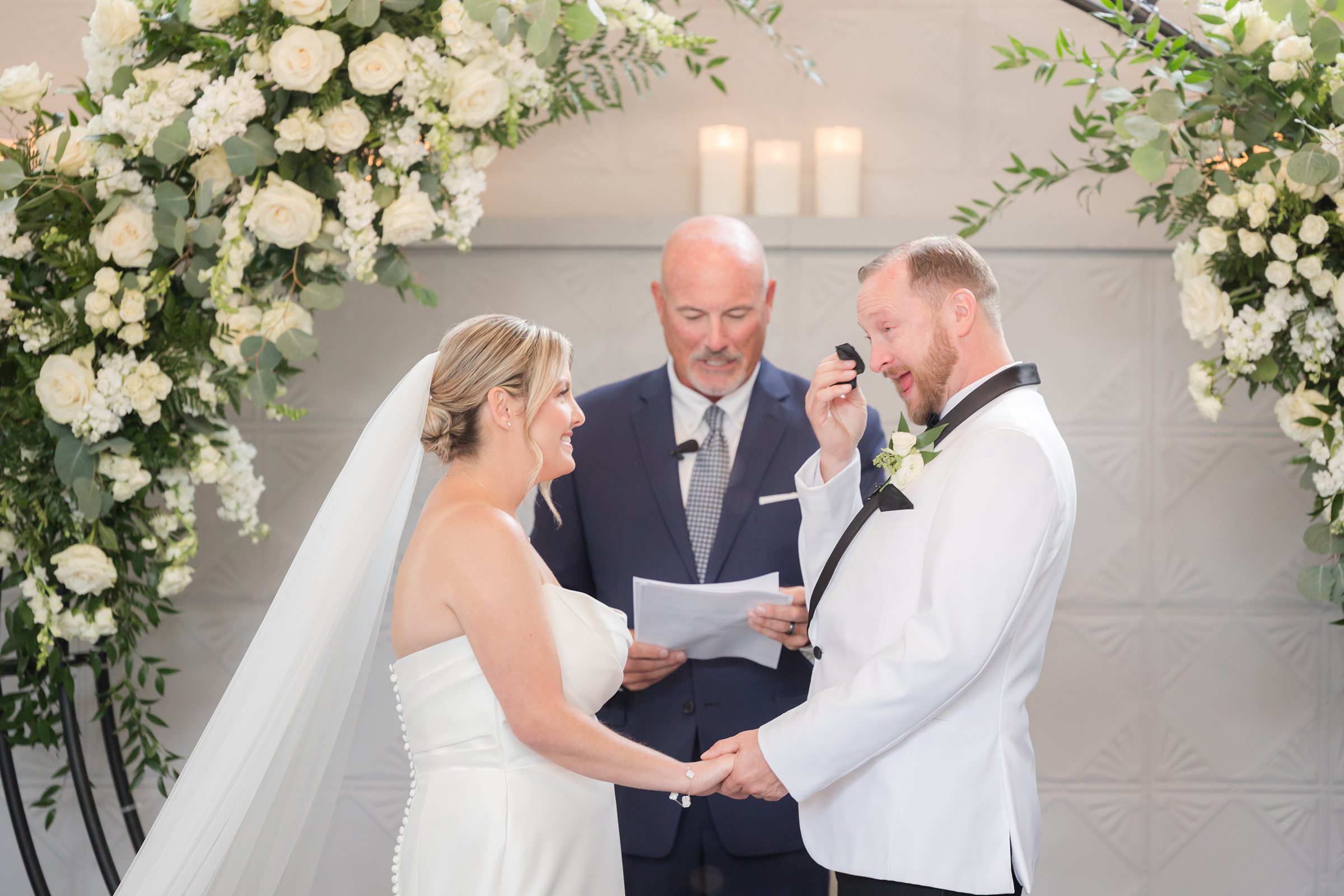 Groom wipes away happy tears while holding his bride’s hands, overcome with emotion during their vows