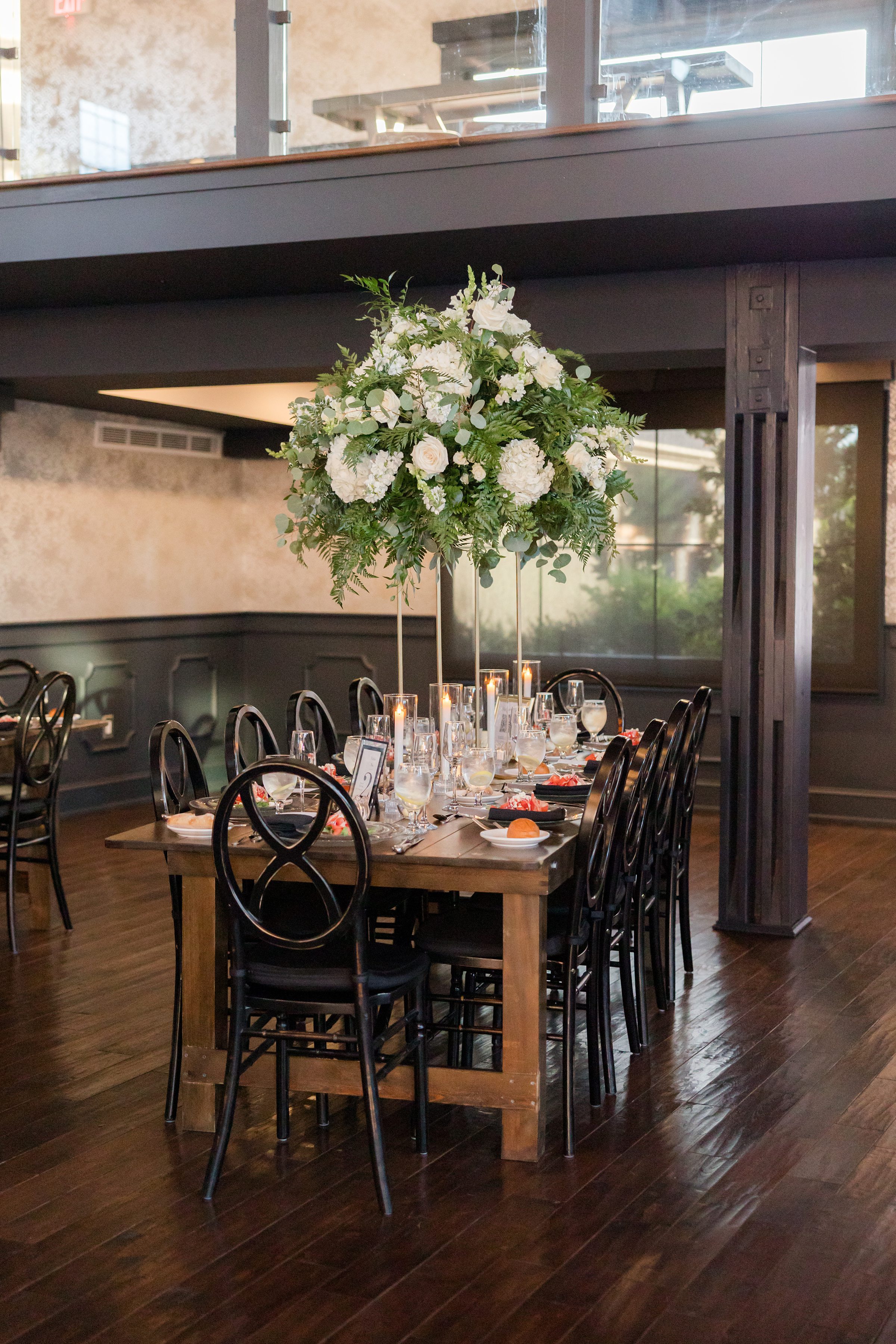 Beautifully set reception table with lush greenery and candles creates an intimate, romantic dining atmosphere.