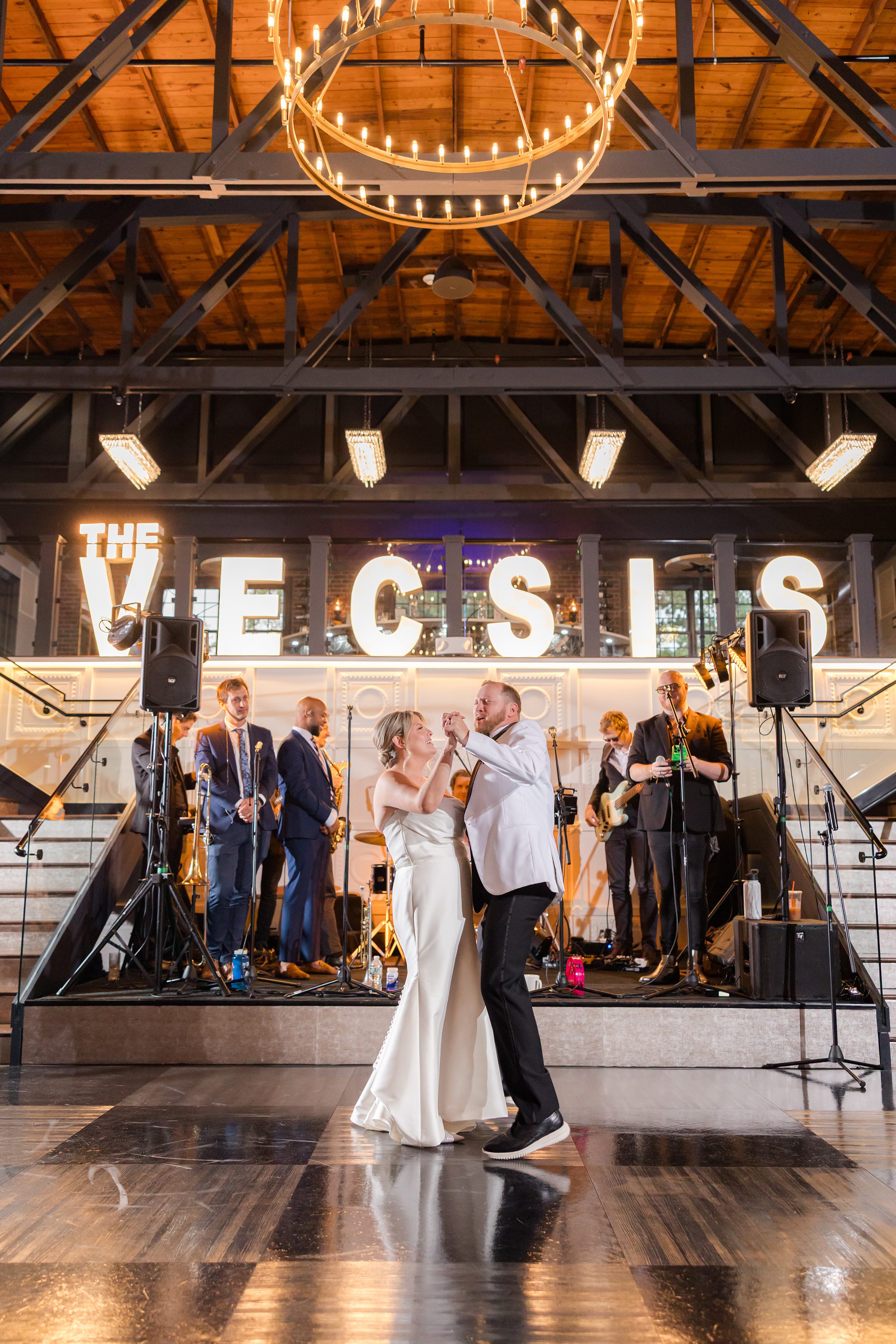 Bride and groom hold each other close as they dance, lost in their own world beneath golden lighting