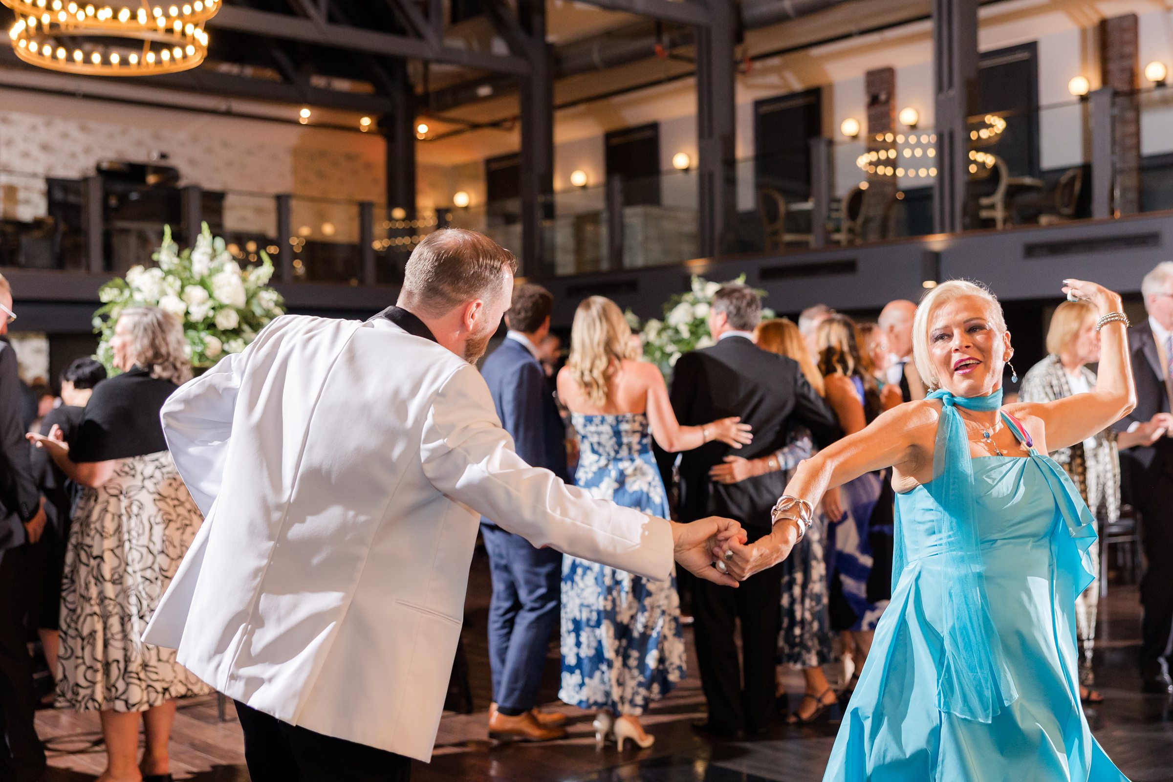 Groom smiles warmly while chatting with guests, immersed in the lively celebration of their marriage.