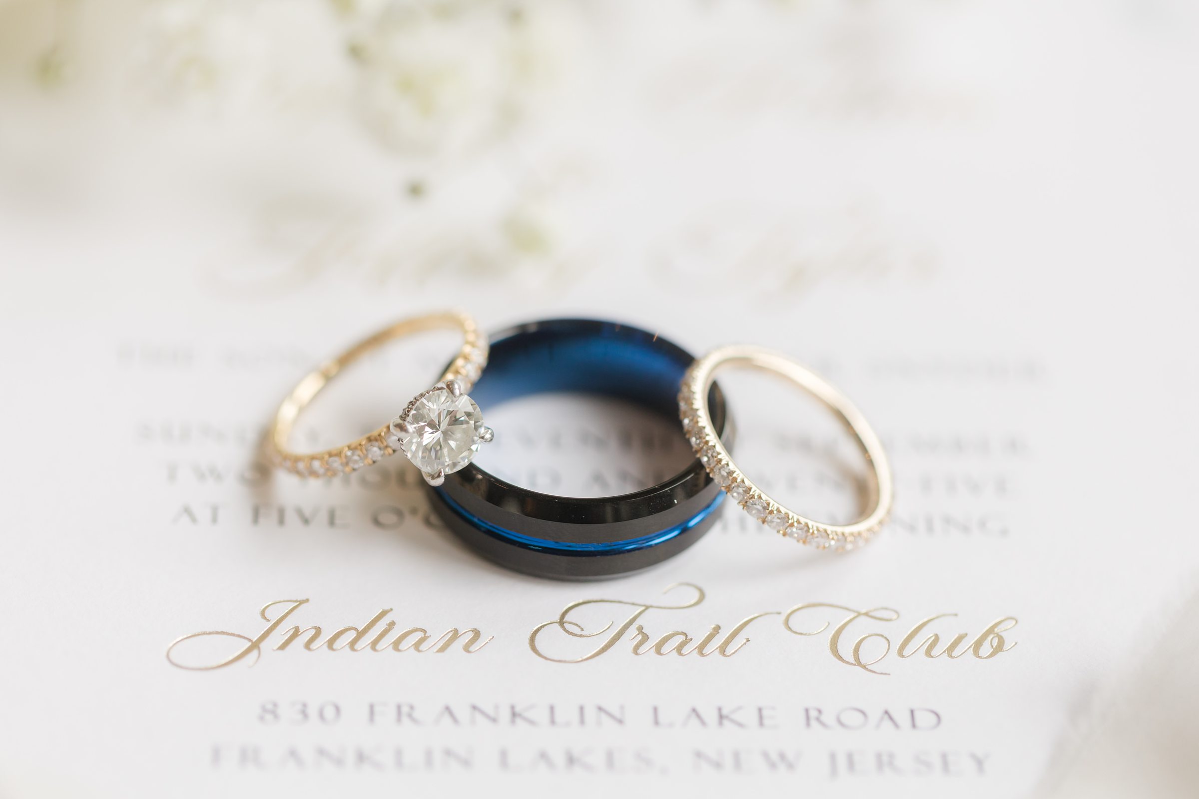 Two golden rings encircle a shimmering diamond atop a wedding invitation, symbolizing an eternal bond sealed in love and devotion
