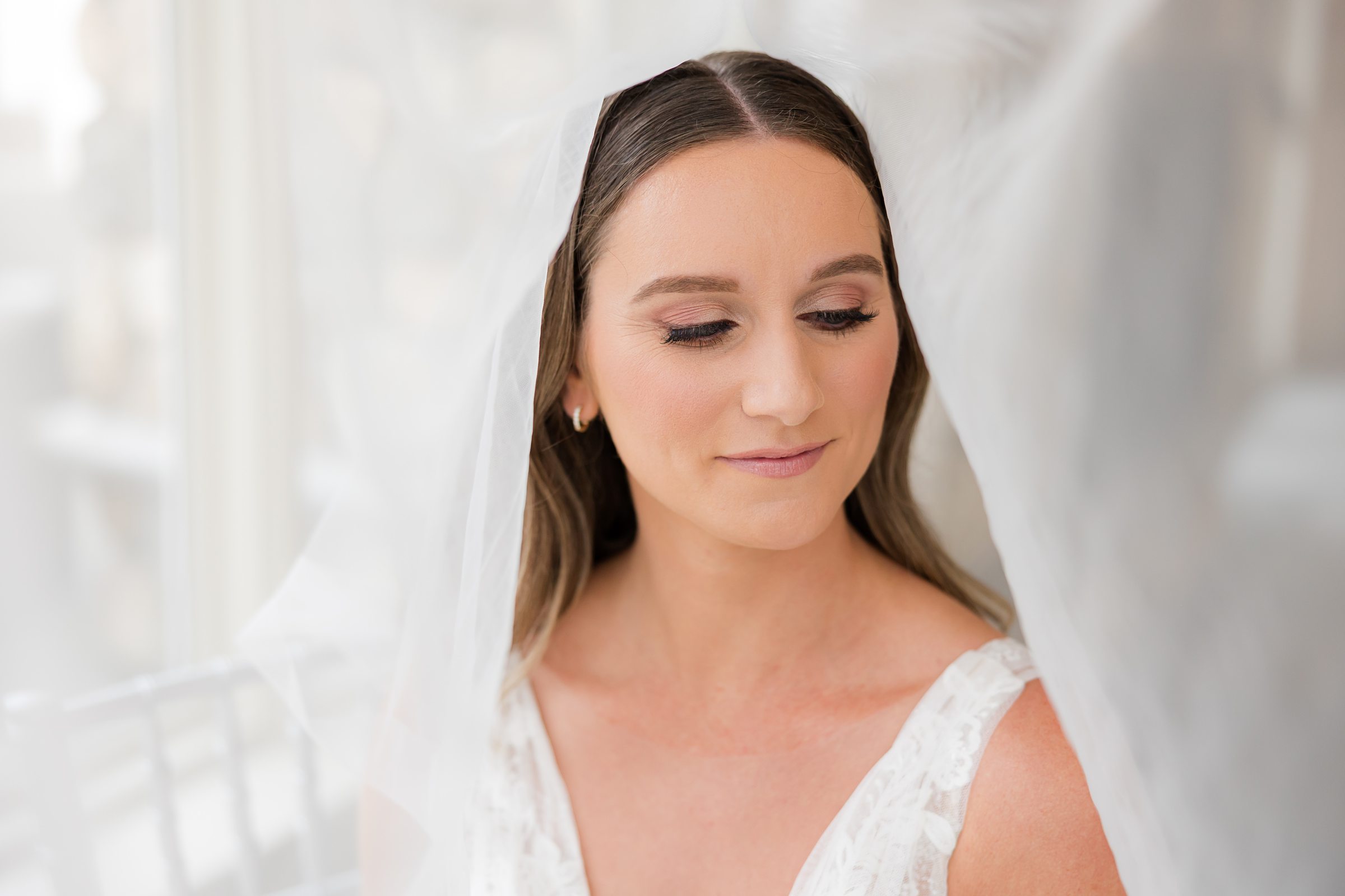 Bride shares a quiet, glowing moment as her veil frames her face, her expression soft and serene