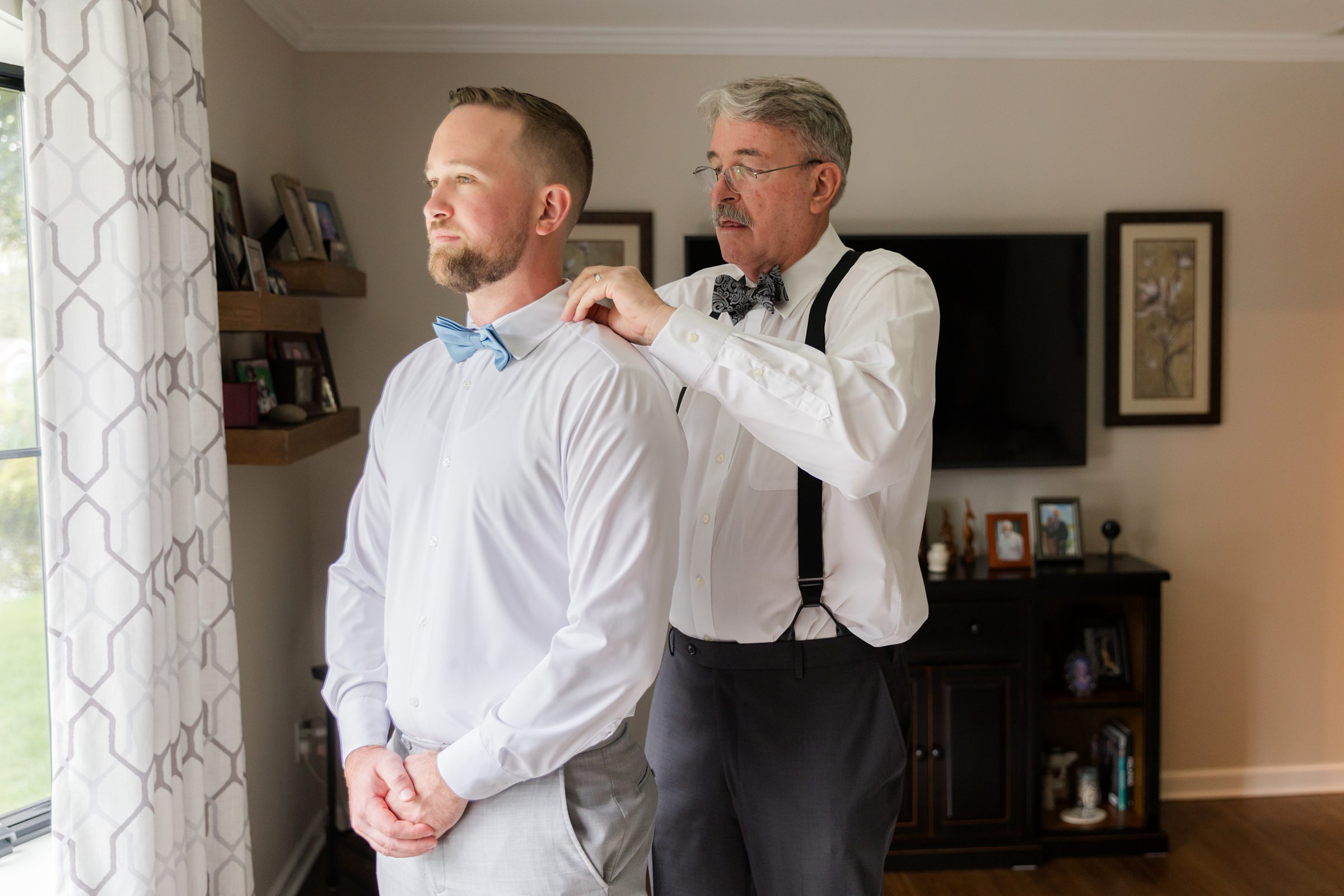 Father gently helps the groom with his tie, a quiet, heartfelt moment filled with pride, love, and the weight of the day ahead