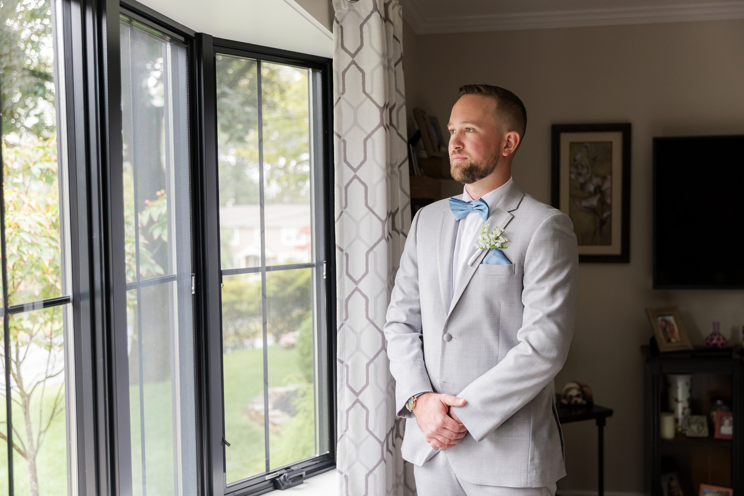 Groom stands by the window, quietly reflecting, anticipation and love softening his expression