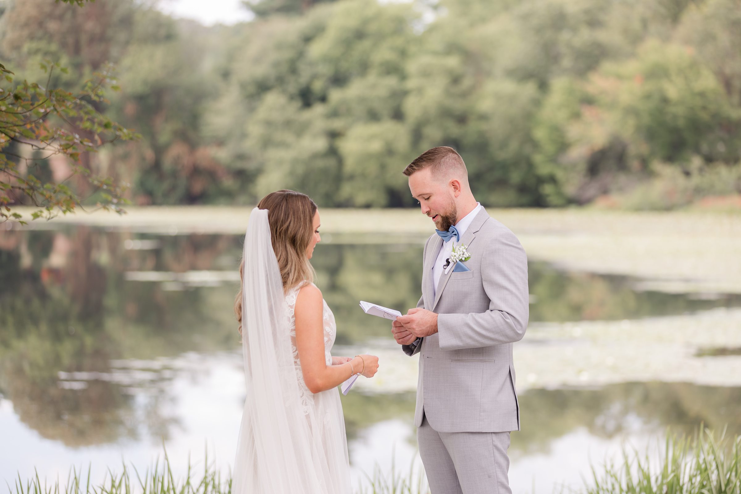 Bride and groom exchange vows, eyes locked and hearts open, with the still water reflecting their promises