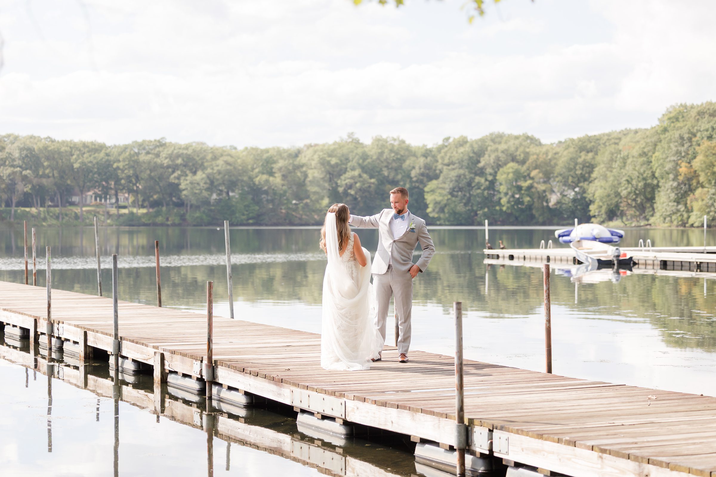 Bride and groom shares a peaceful moment by the water, framed by nature and soft reflections