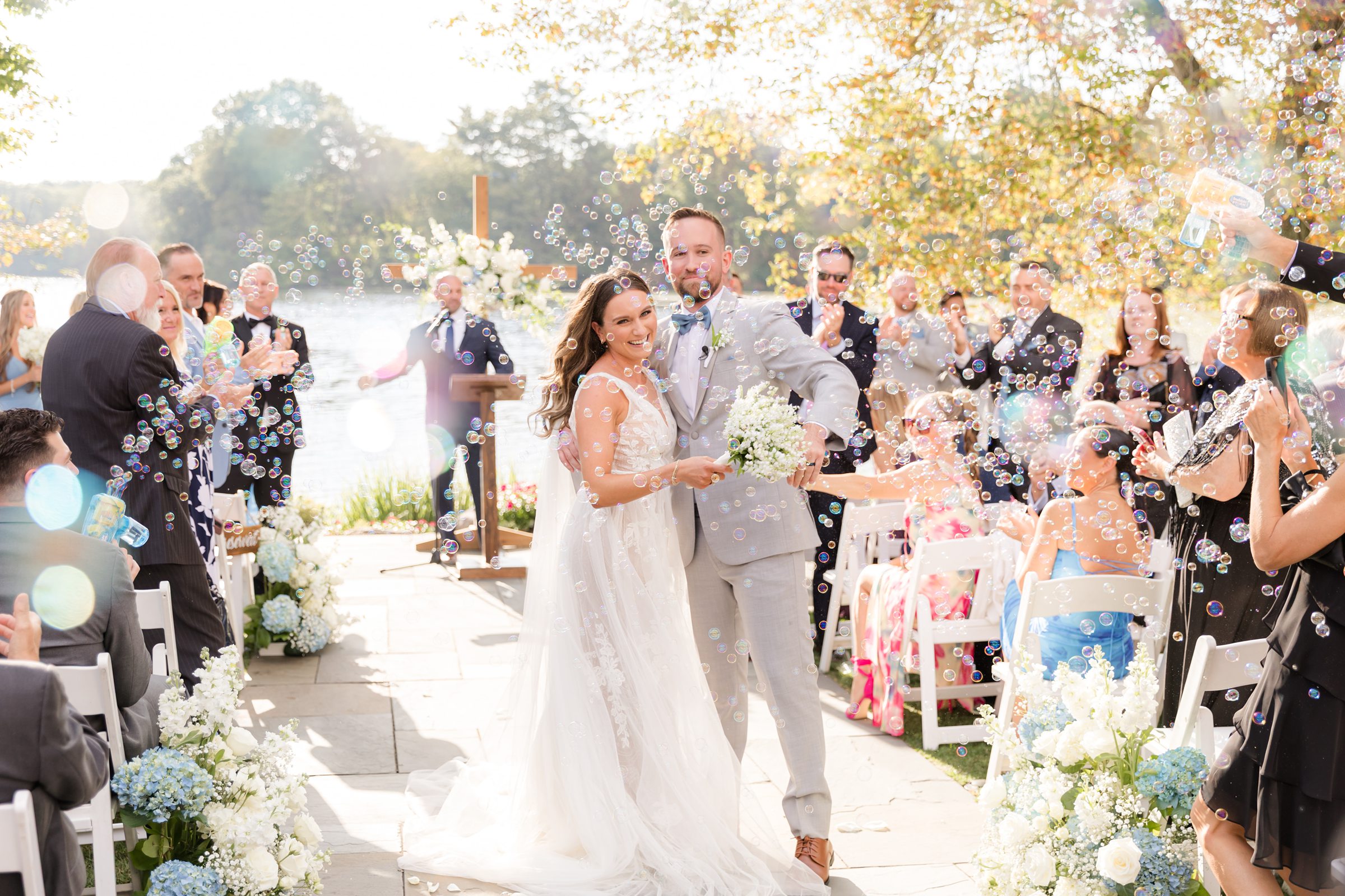 Newlyweds walking down the aisle smiling while guests celebrate and toss petals