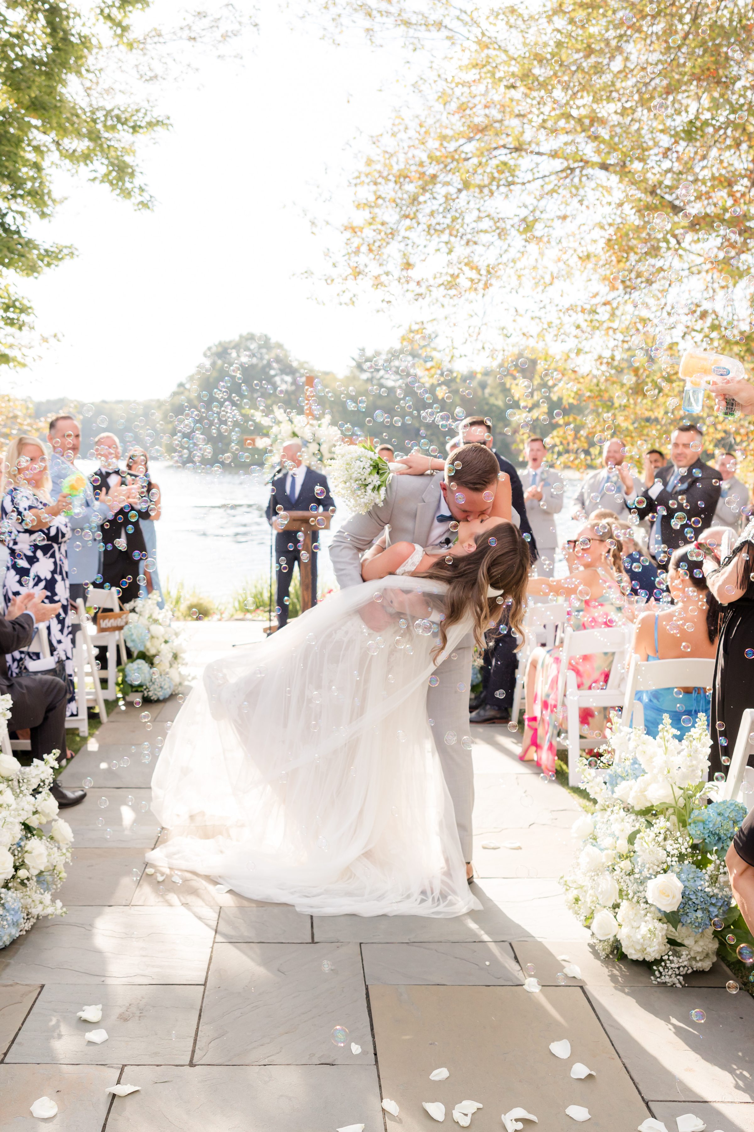 Groom dips the bride as petals fall around them, capturing a joyful, cinematic moment of love