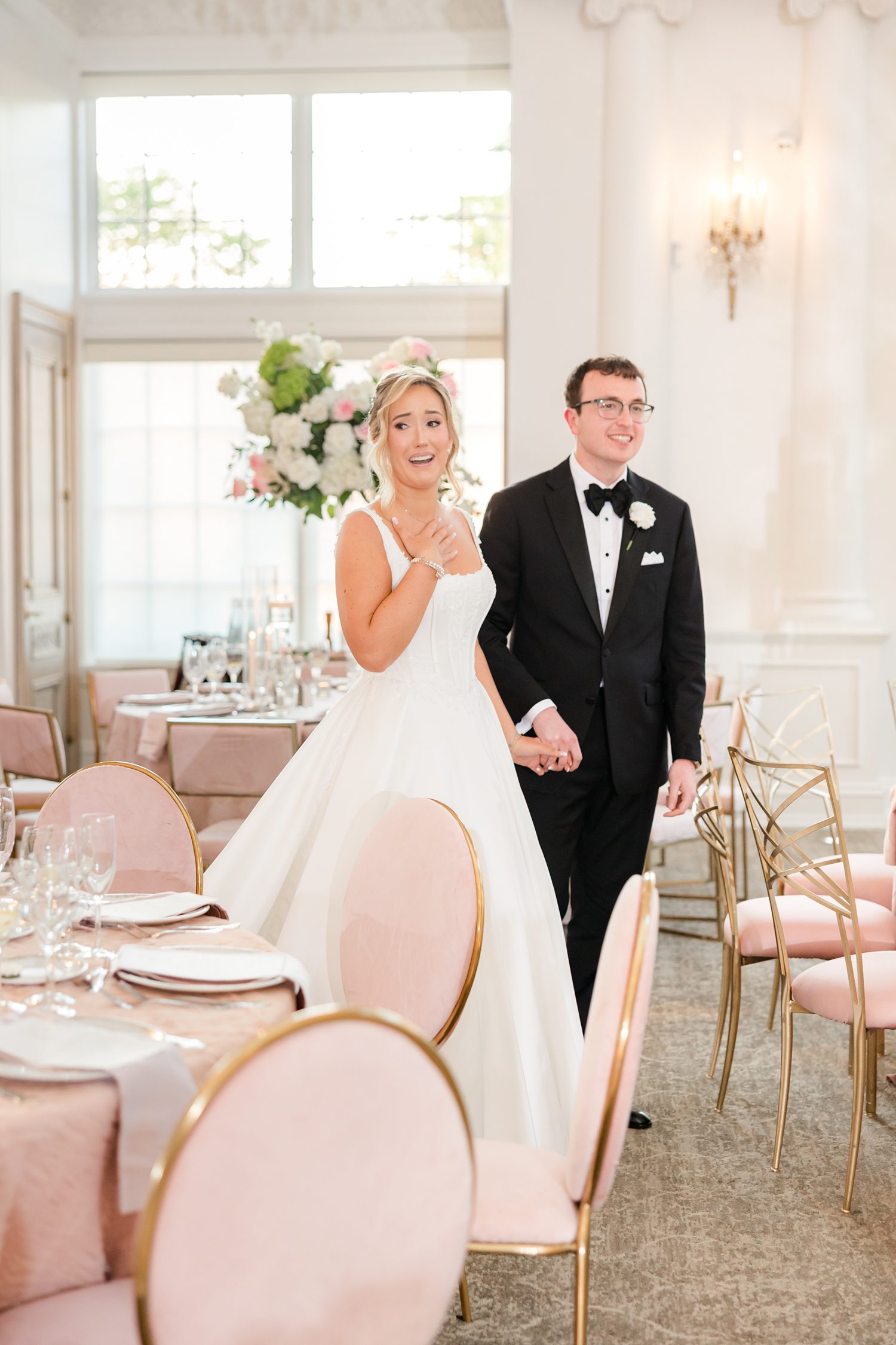 Bride and groom's first appearance and wedding reception with rose pink, white and gold themed chairs and table set up