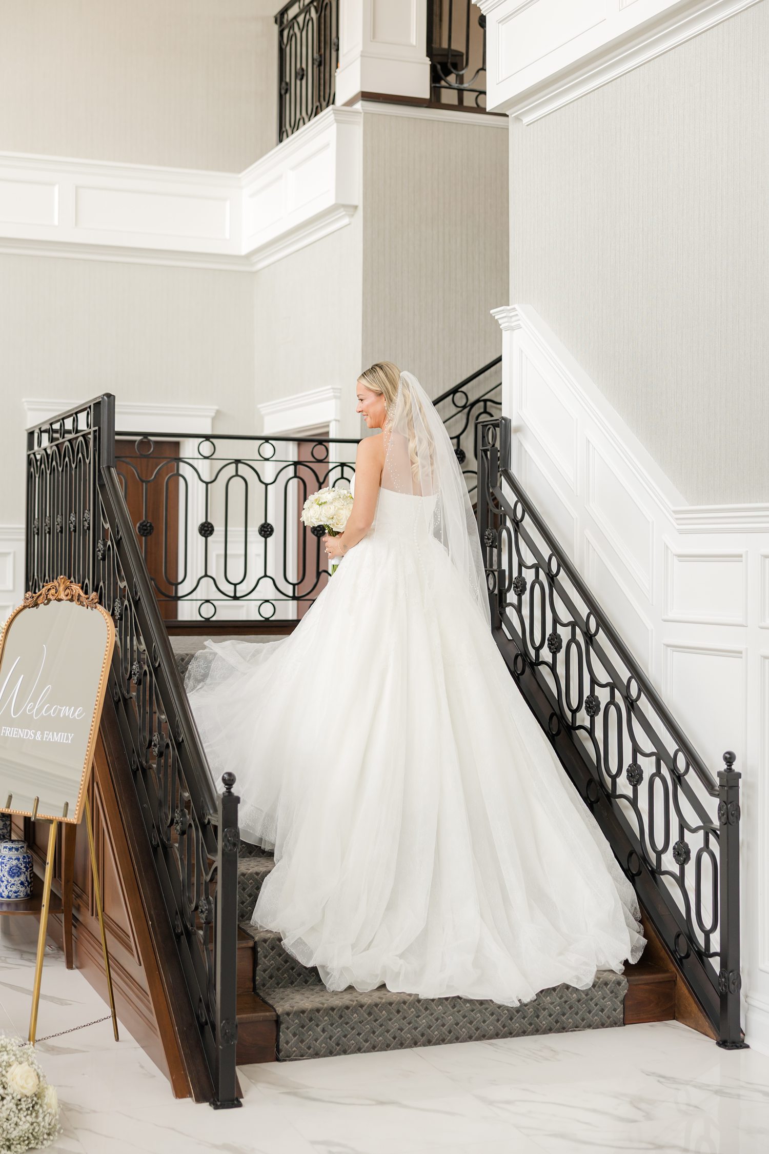 Bride posing in strapless wedding gown and ascending in staircase with elegant wedding dress inside luxury venue