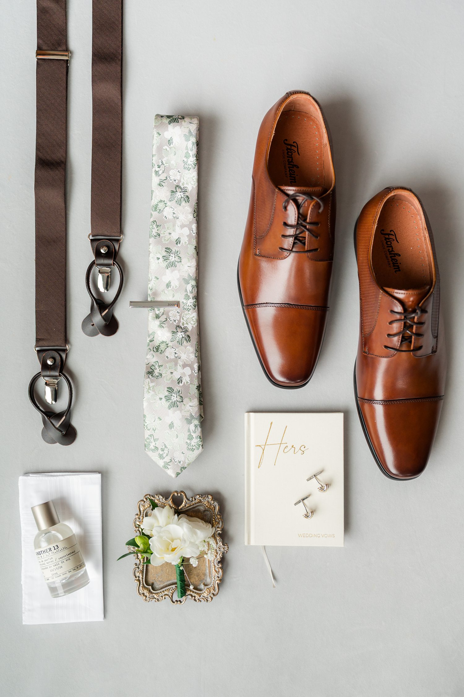 Groom accessories flat lay with brown dress shoes, watch, and wedding details