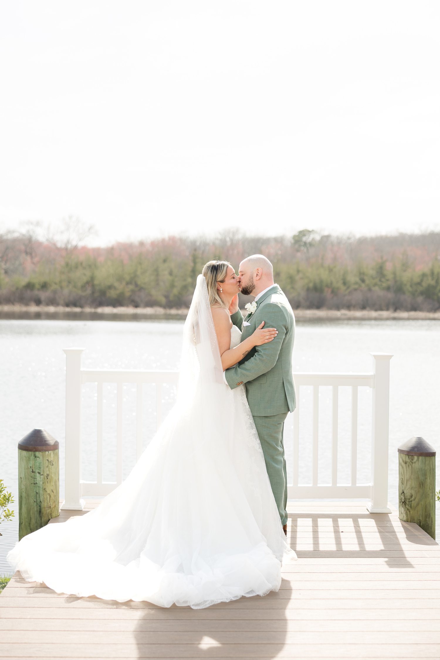 Bride and groom kissinng on dock with scenic waterfront wedding view